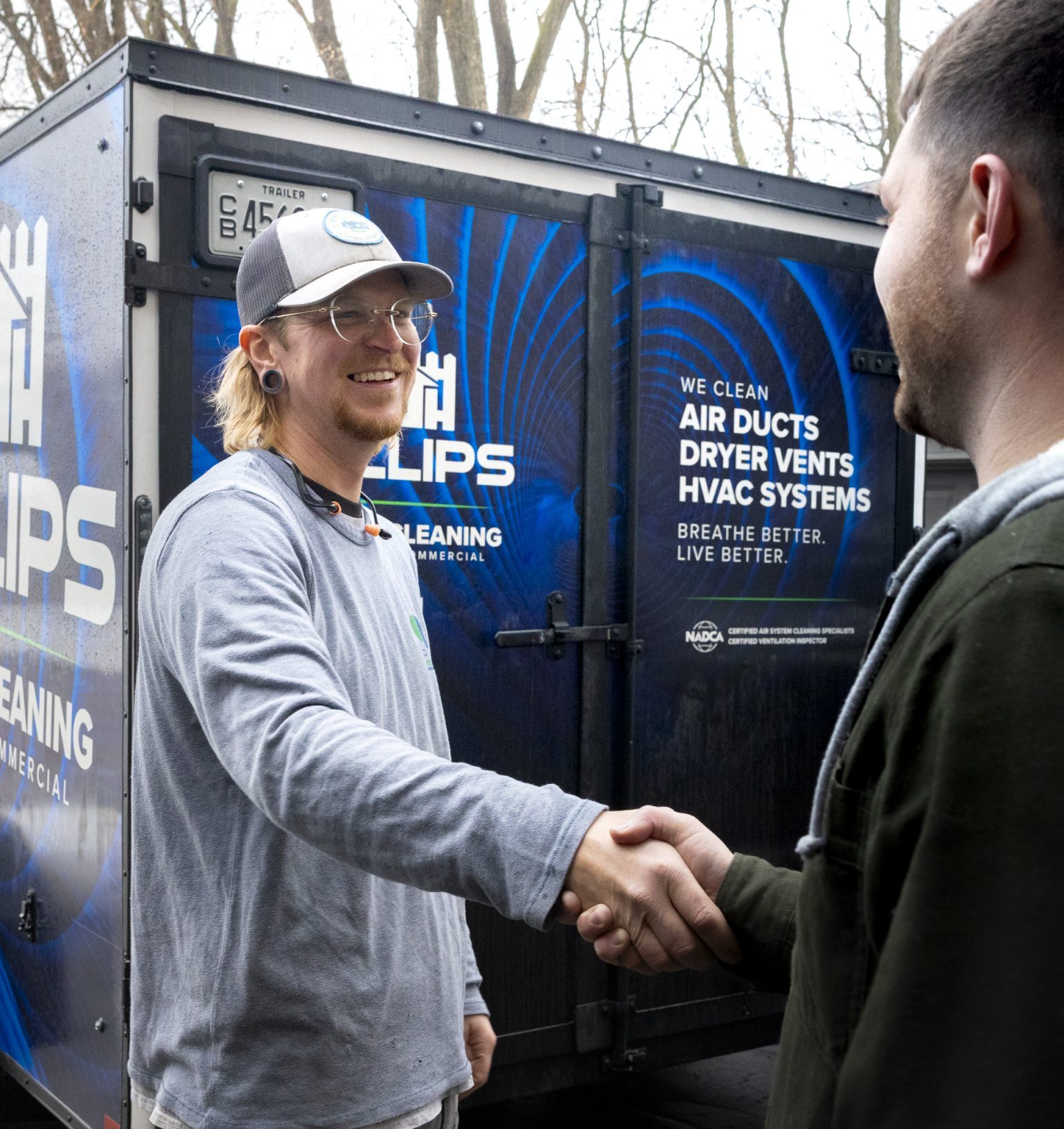 Technician shaking hands with customer by service trailer
