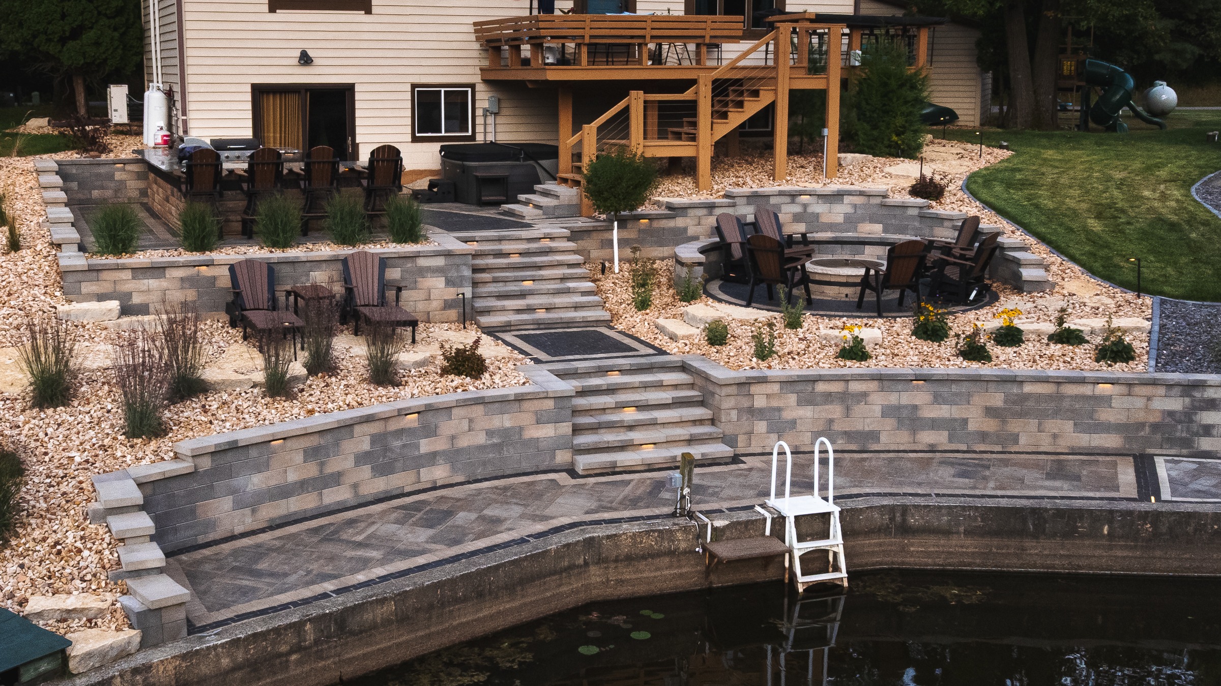 Tiered backyard patio with fire pit and pond
