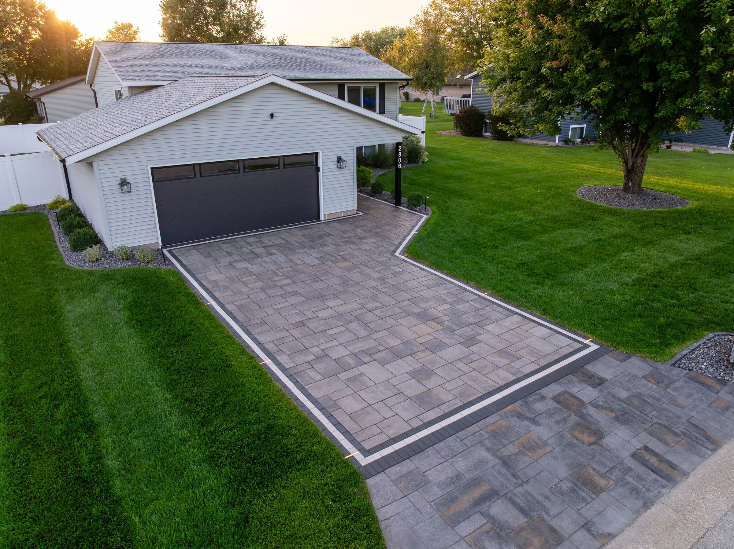 Suburban home with modern paver driveway at sunset