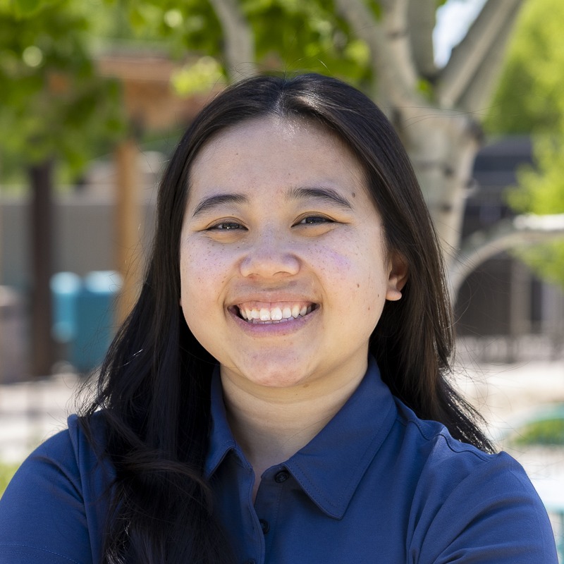 Smiling woman outdoors with trees in background