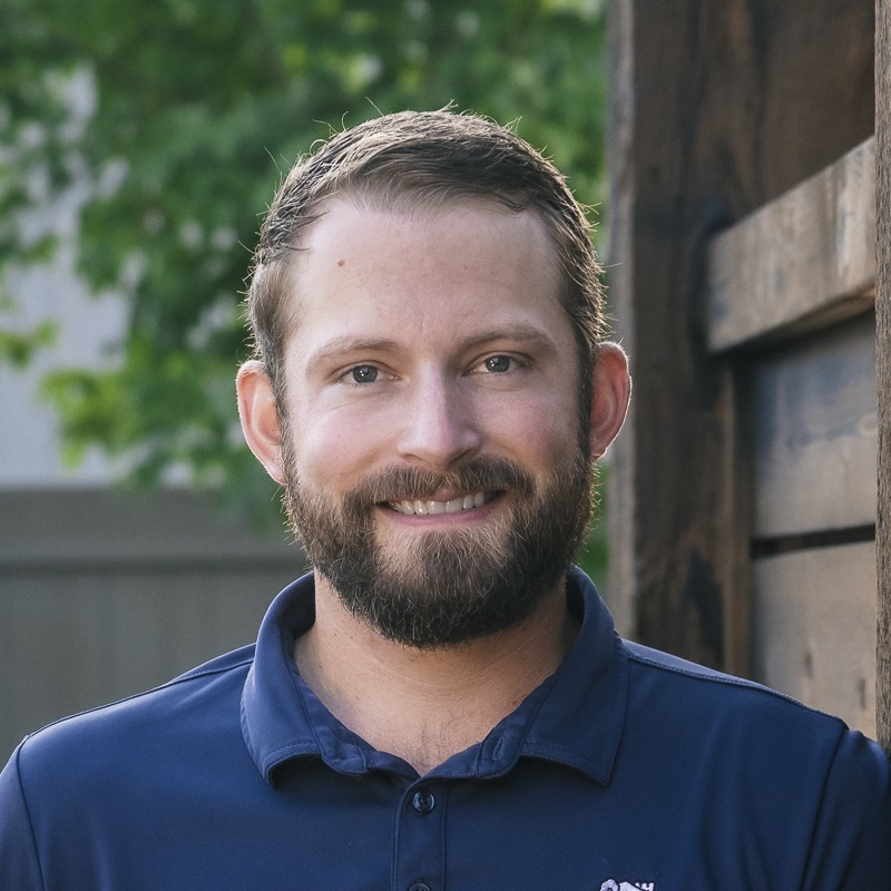 Smiling bearded man in navy polo outdoors