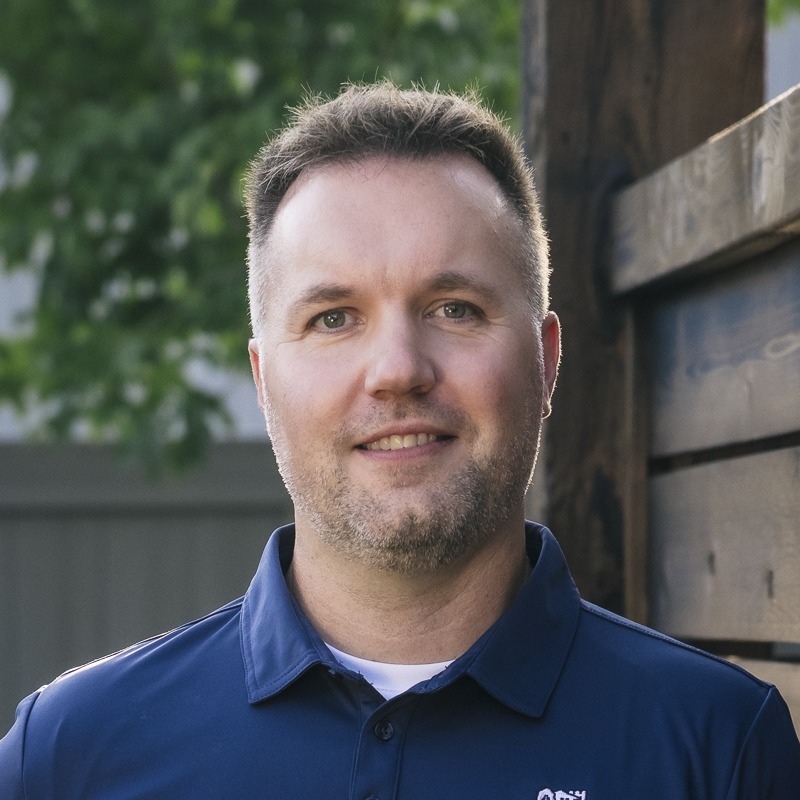 Smiling man in navy polo outdoors