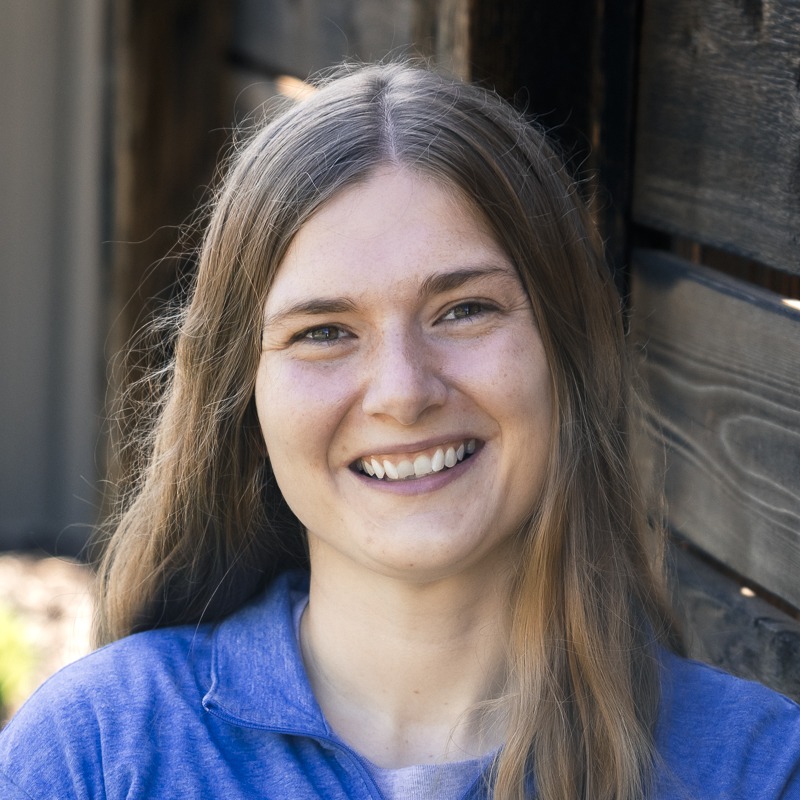 Smiling woman with long hair by wooden wall