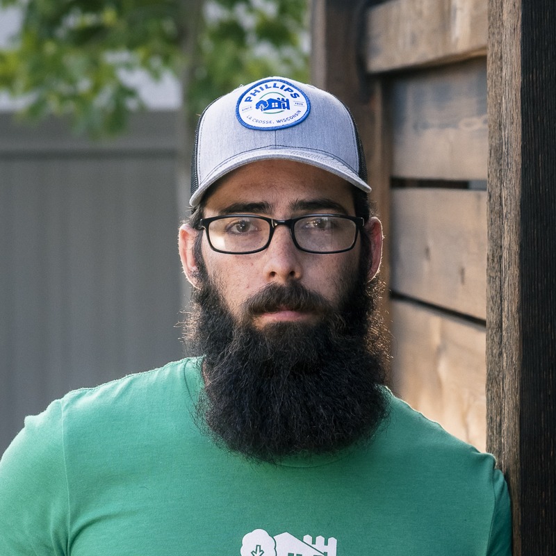 Bearded man wearing glasses and gray cap outdoors