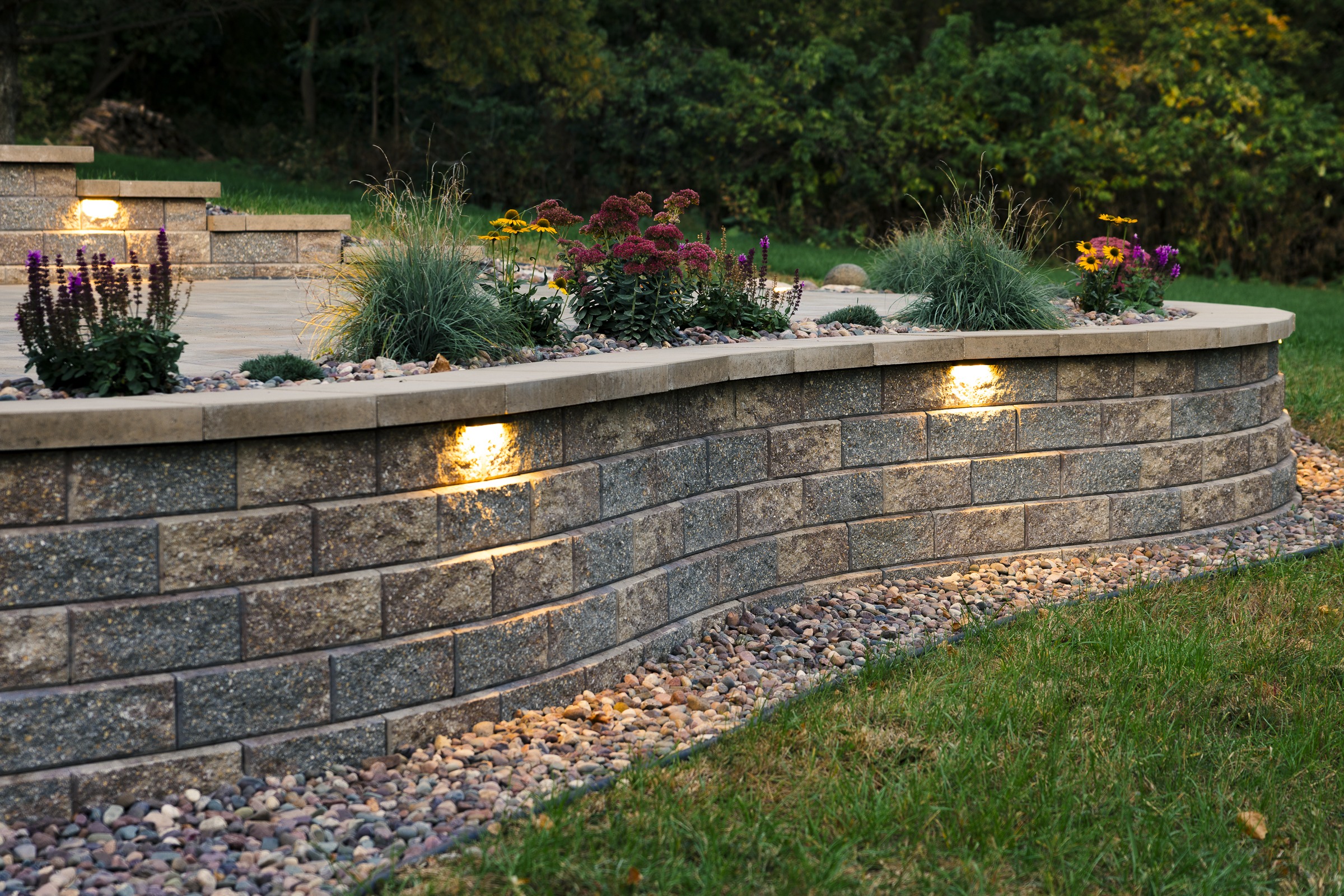 Curved stone retaining wall with garden lighting