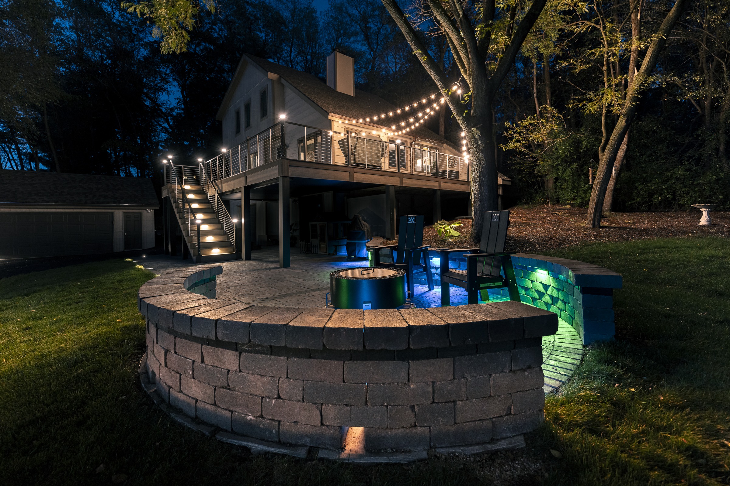 Modern backyard patio with fire pit at night
