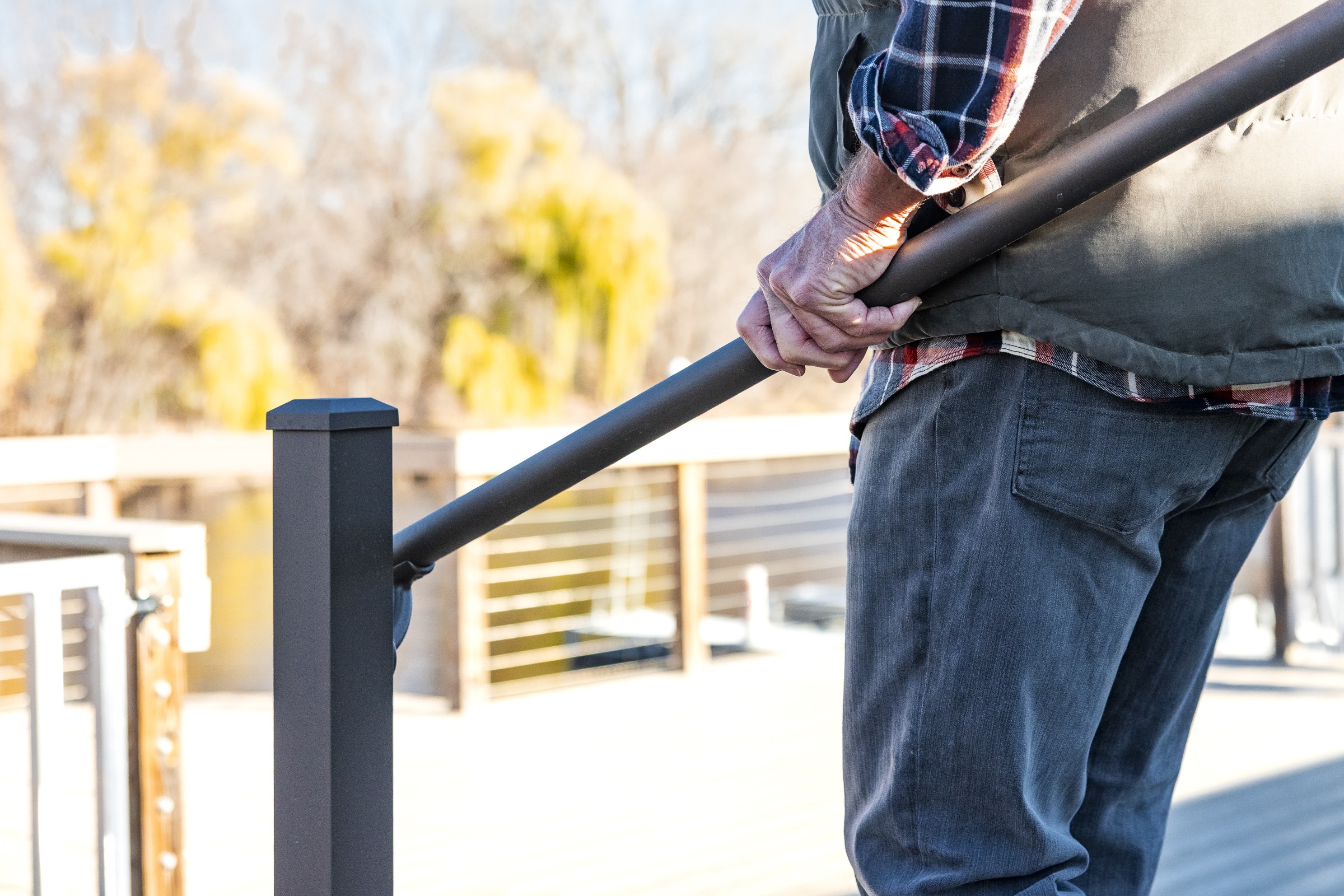 Person holding railing on outdoor deck steps