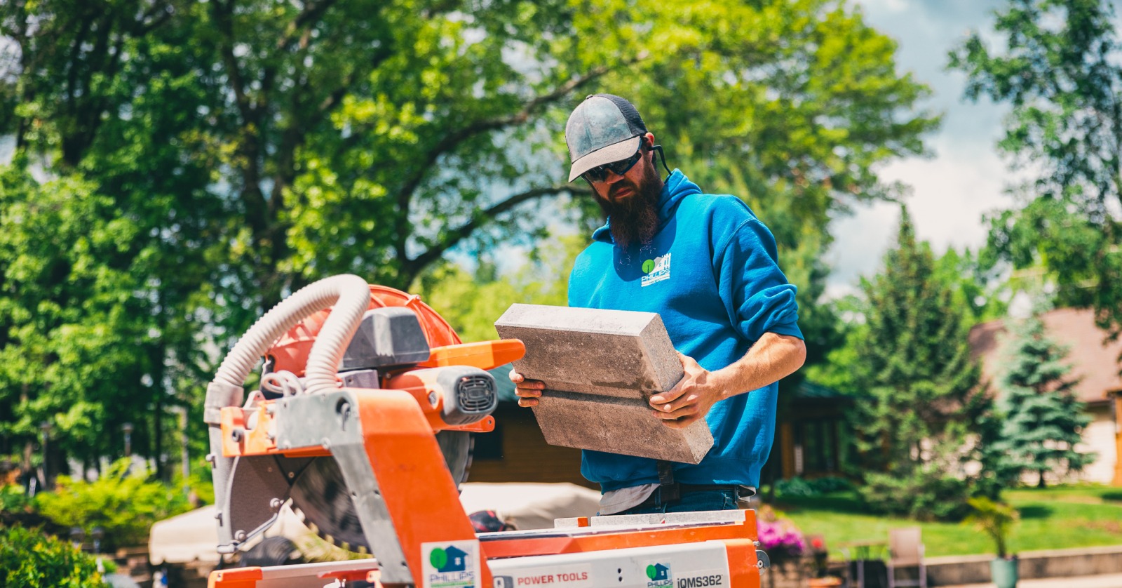 Worker cutting concrete block with masonry saw outdoors