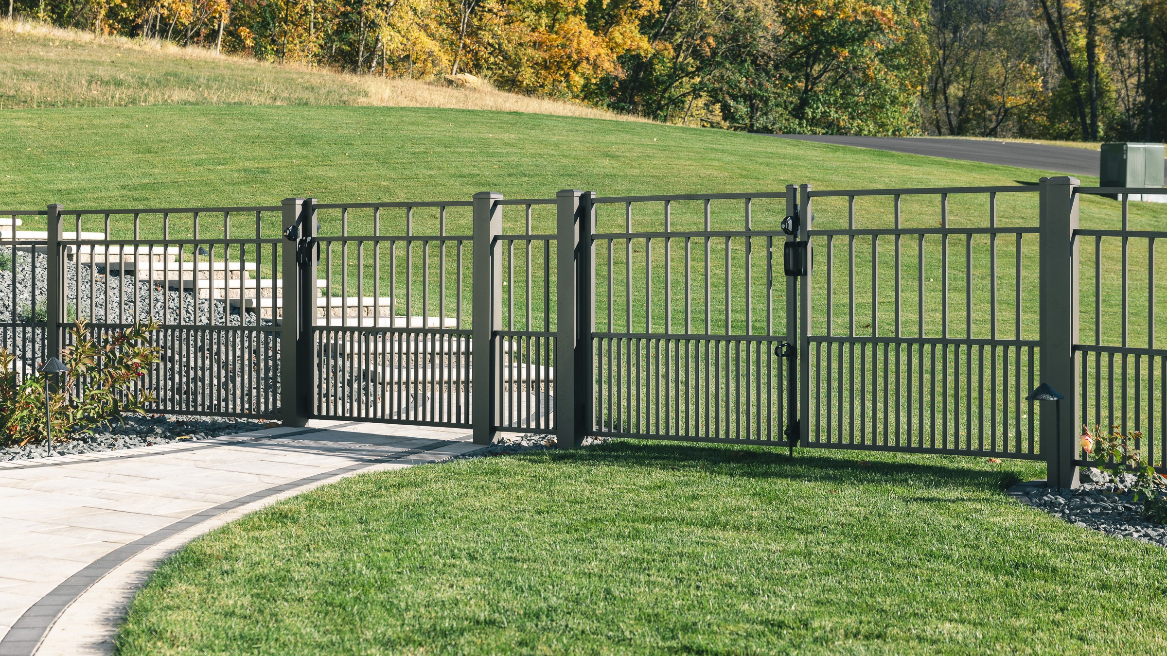 Black metal fence surrounding landscaped backyard lawn