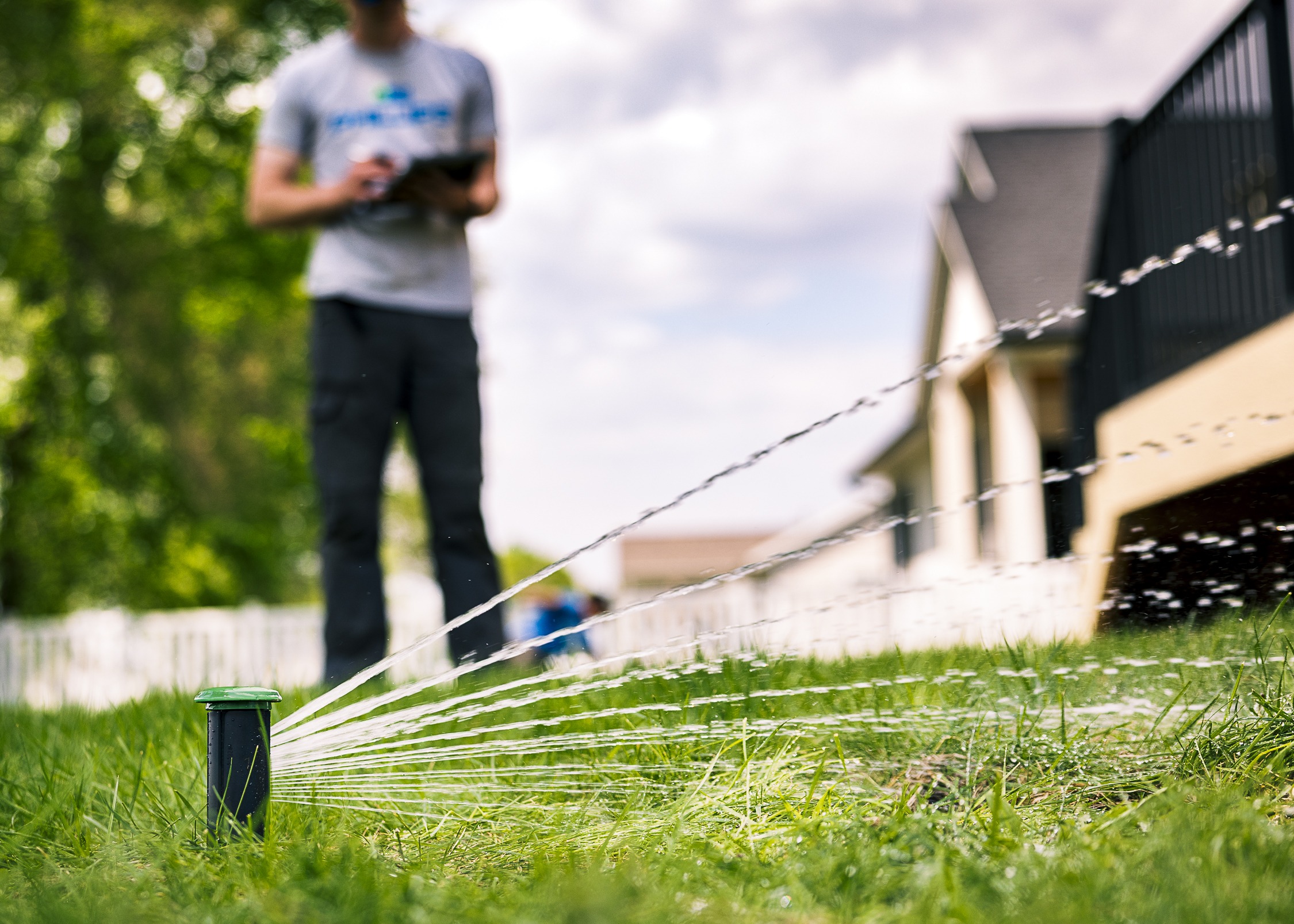 Lawn sprinkler watering grass near suburban home