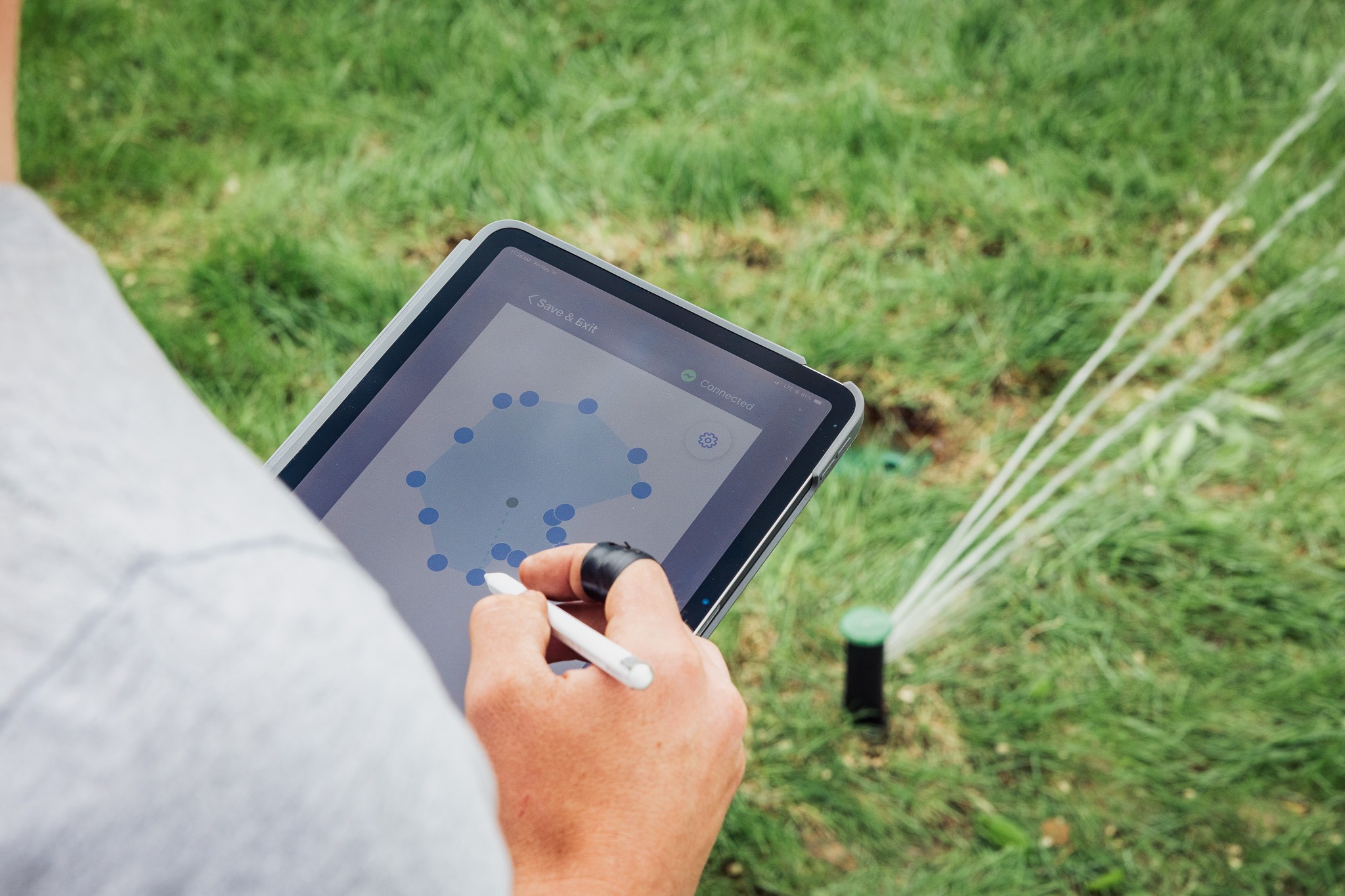 Person controlling lawn sprinkler system on tablet