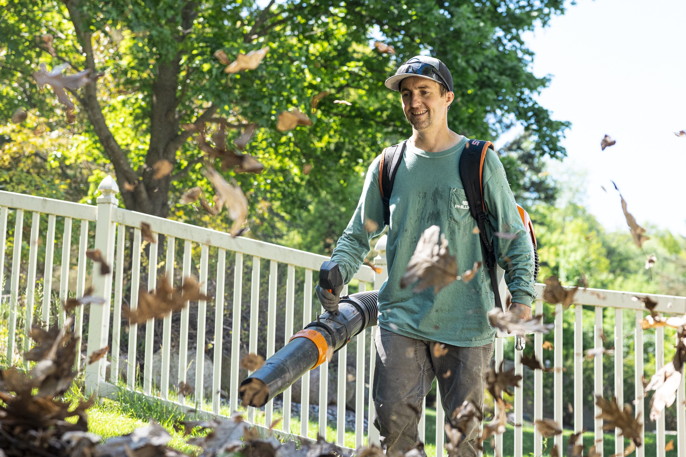 Man using leaf blower in sunny backyard