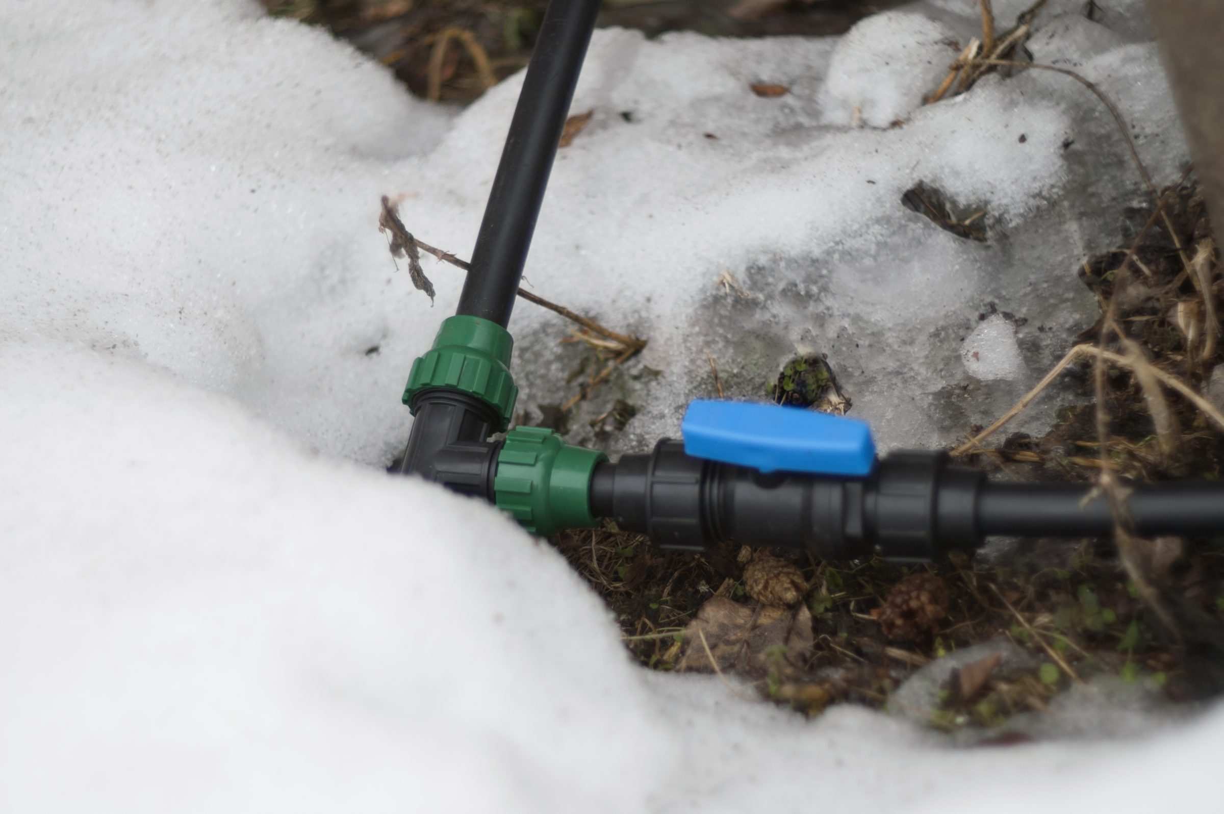Irrigation pipe valve surrounded by melting snow
