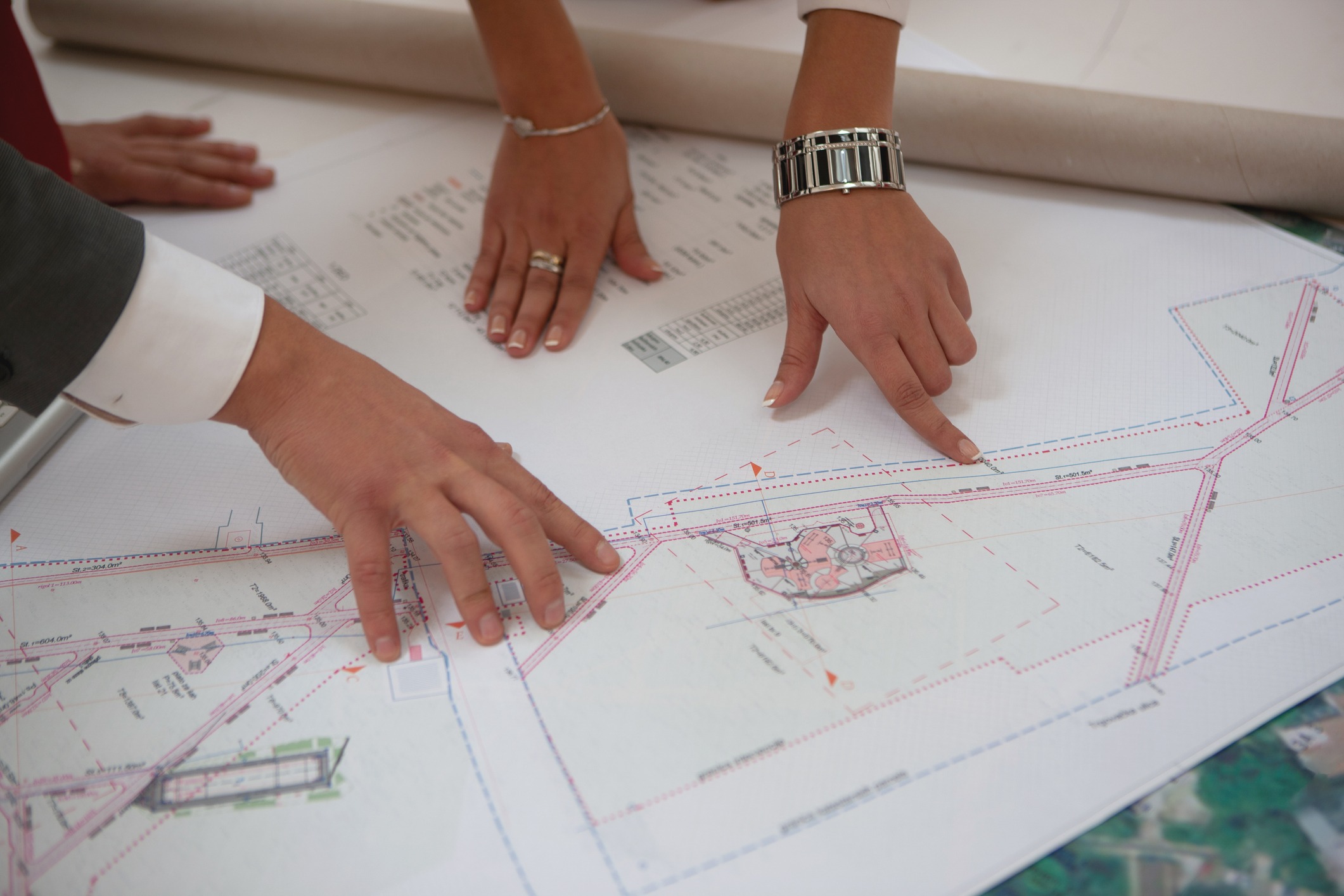 Hands pointing at architectural site plan blueprint