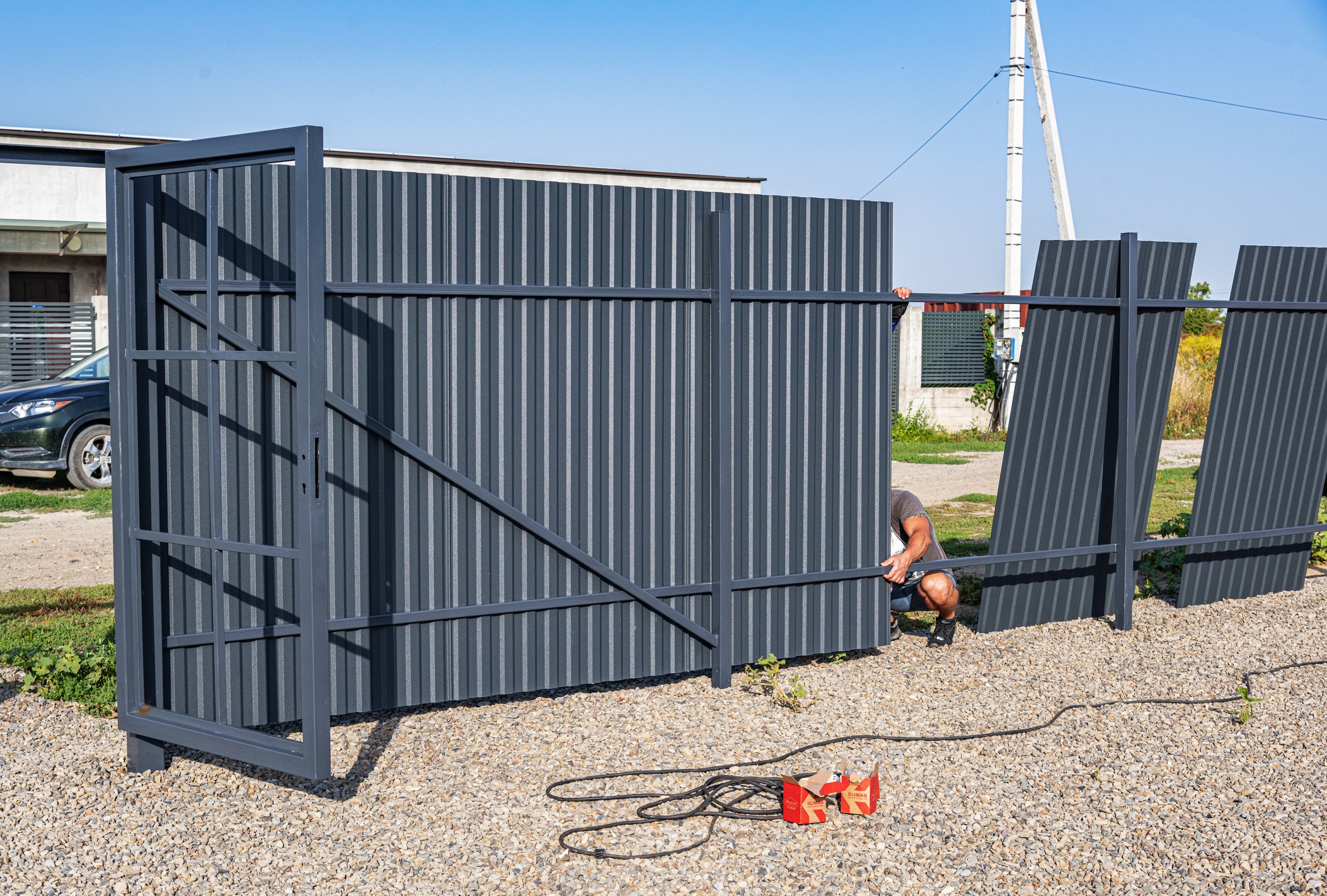 Man installing large gray metal fence panels