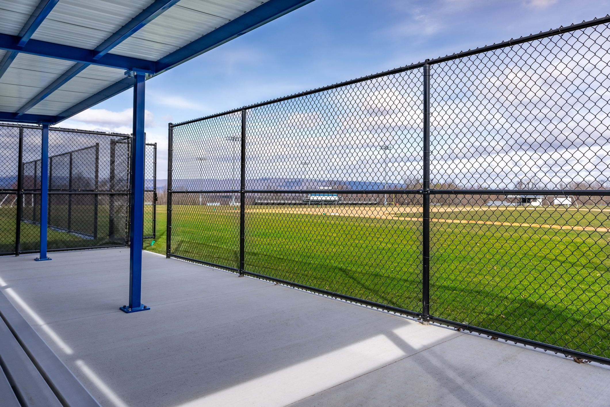 Covered dugout beside fenced baseball field