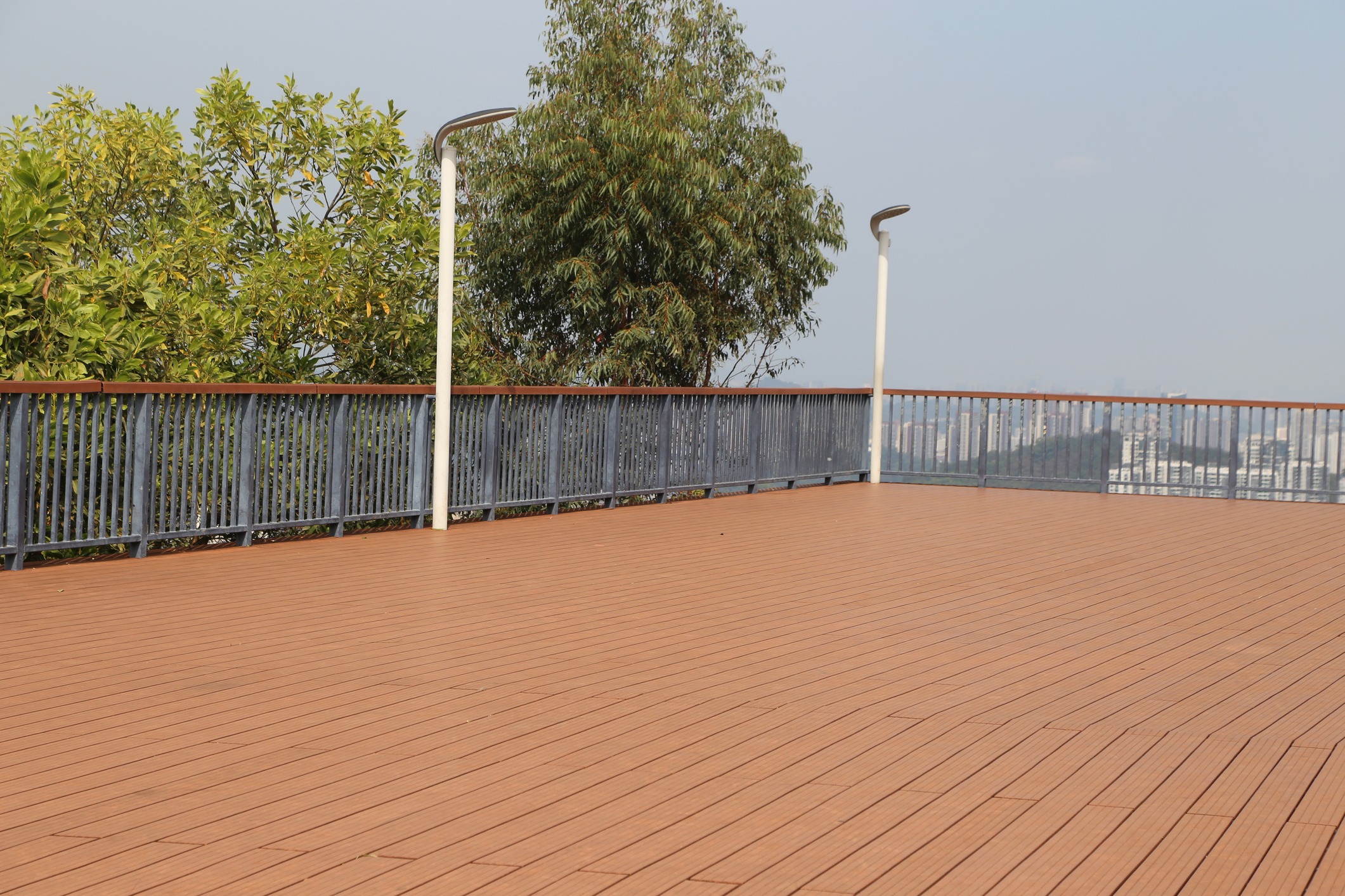 Wooden rooftop deck with railing and city view