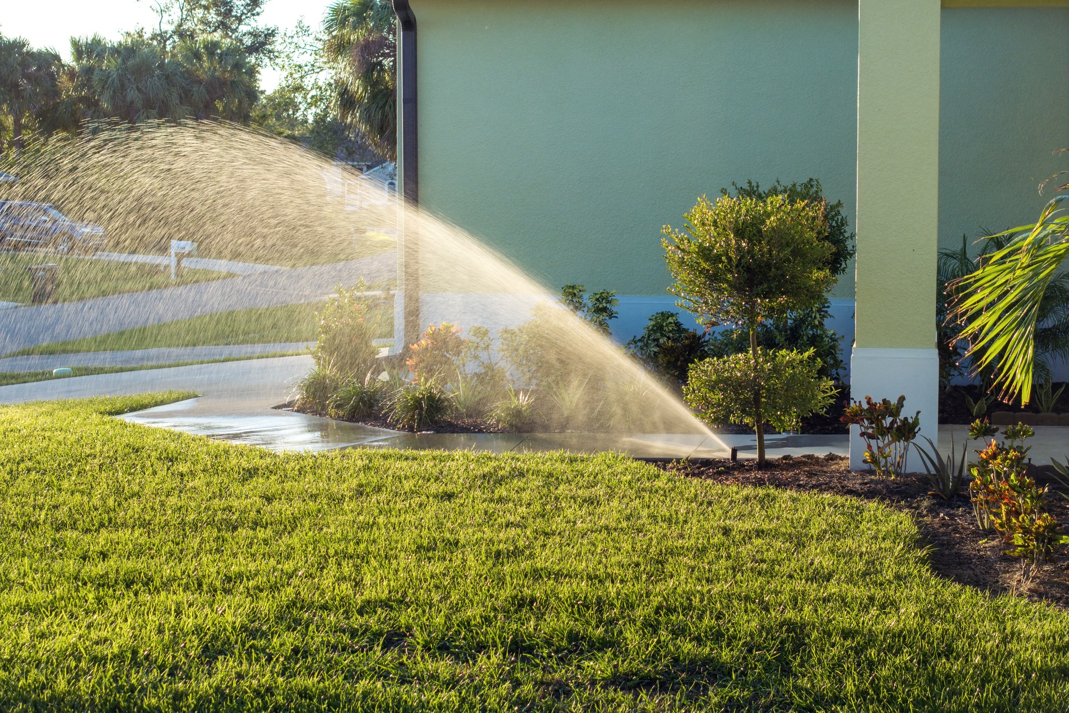 Lawn sprinkler watering green grass near house