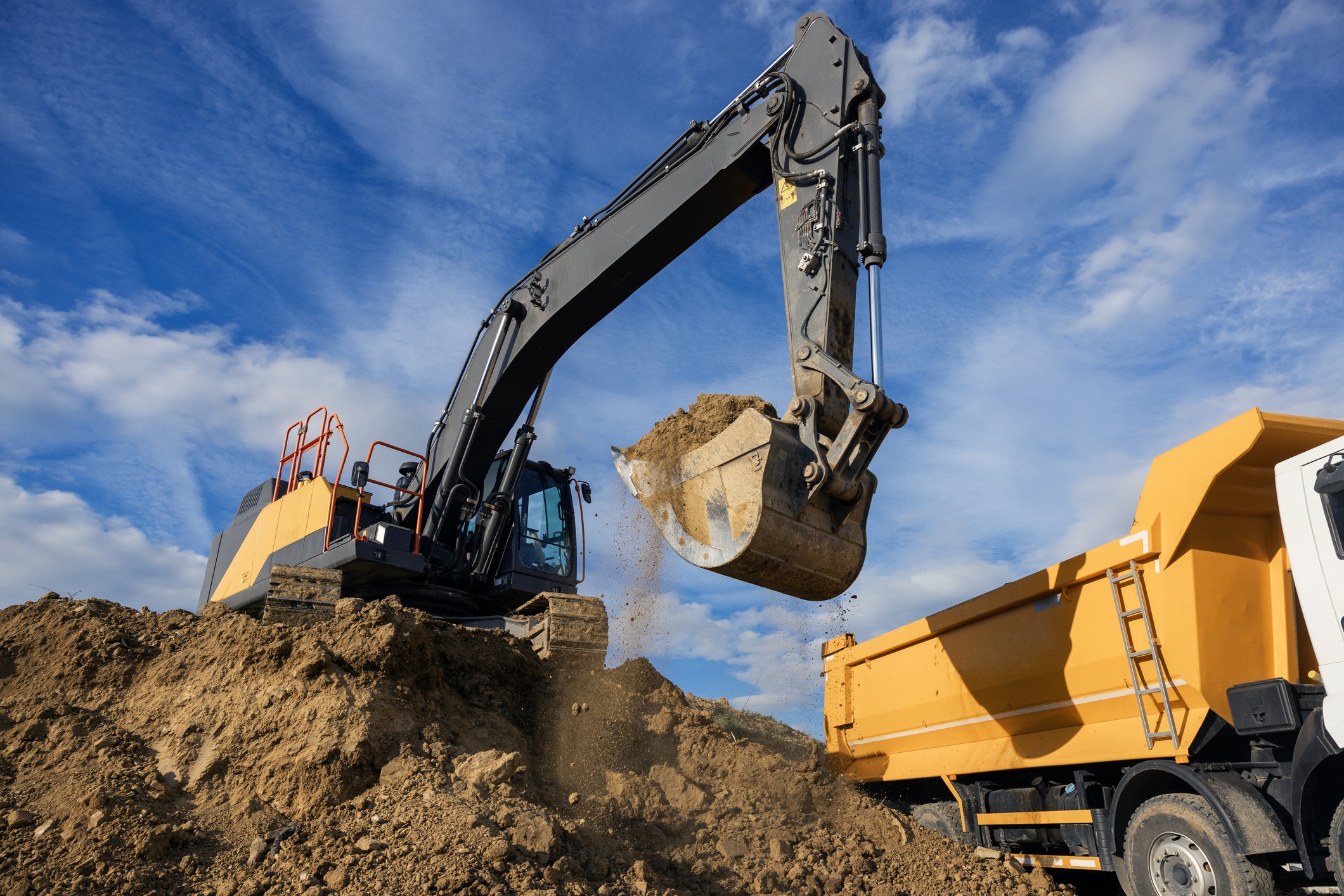 Excavator loading dirt into dump truck