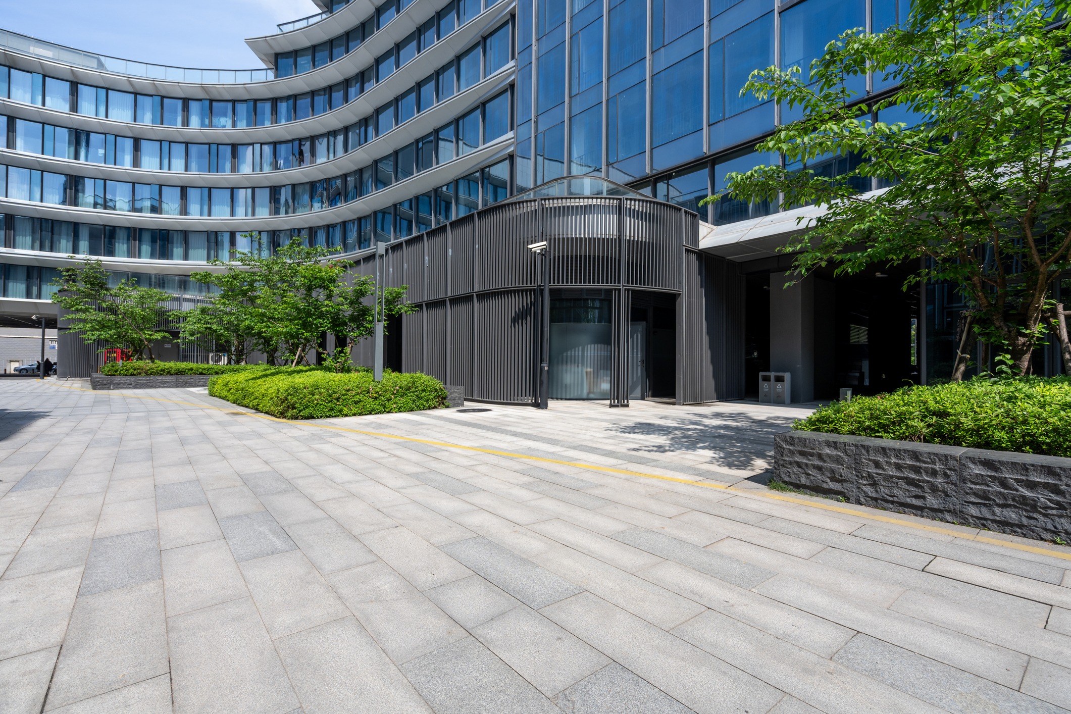 Modern curved glass office building exterior with landscaping