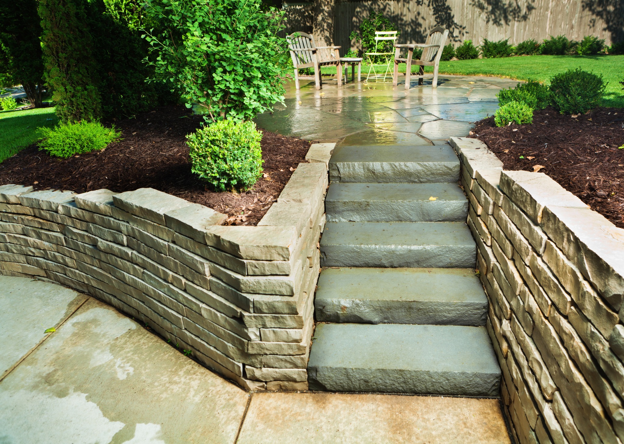 Stone steps leading to backyard patio with chairs