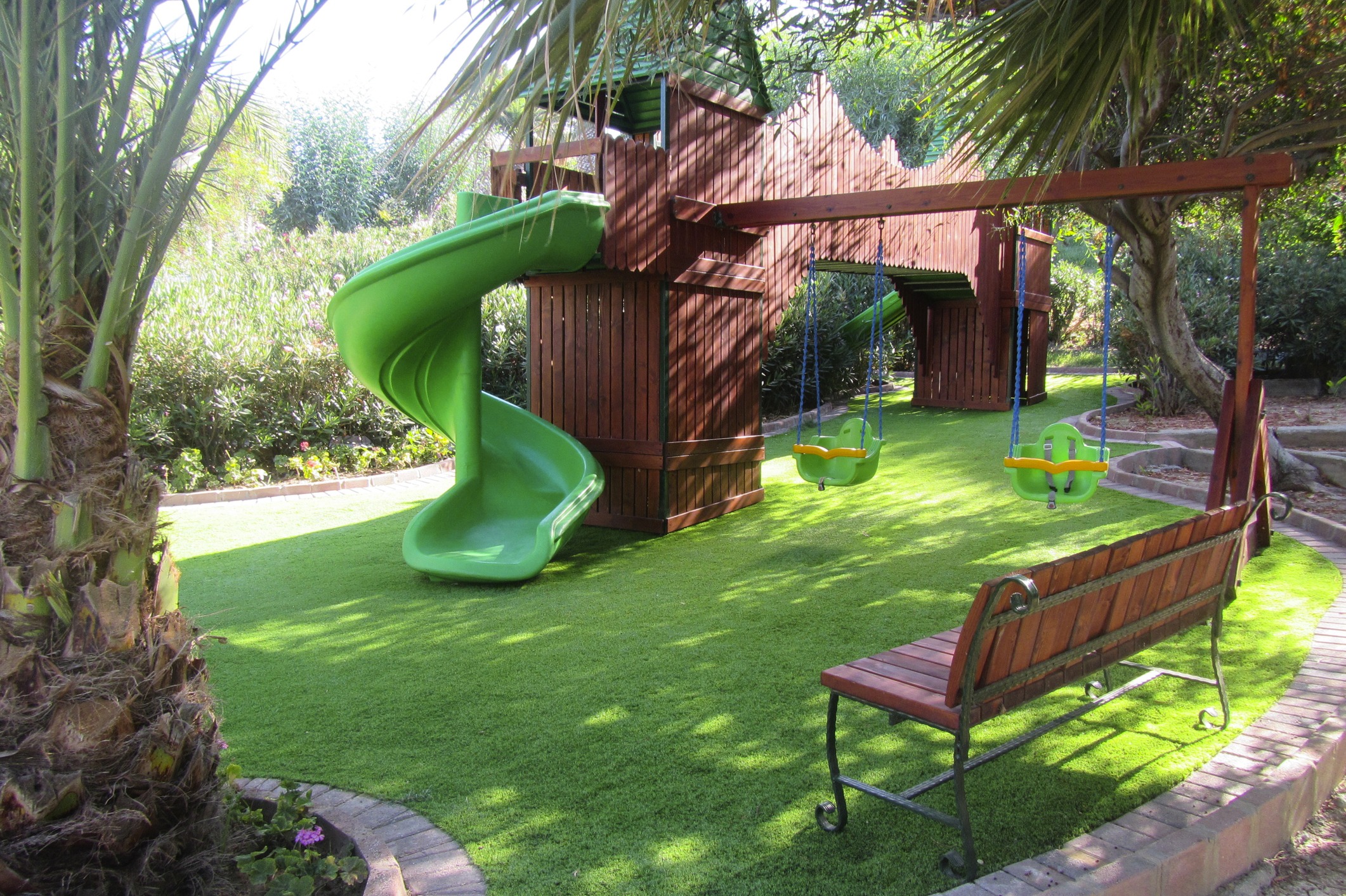 Backyard wooden playset with green slide and swings