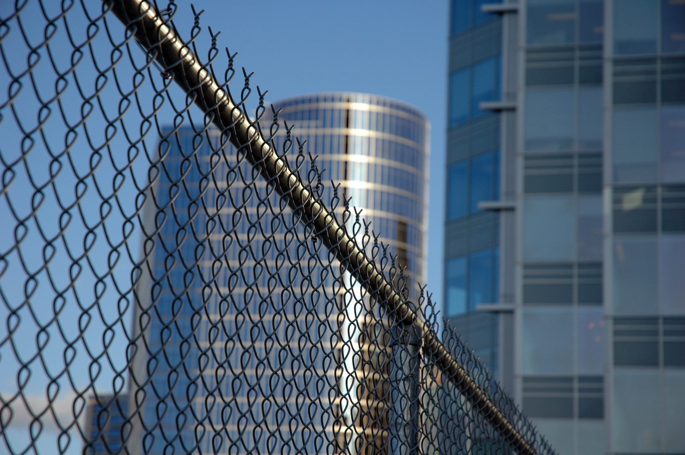 Chain-link fence with modern glass buildings behind