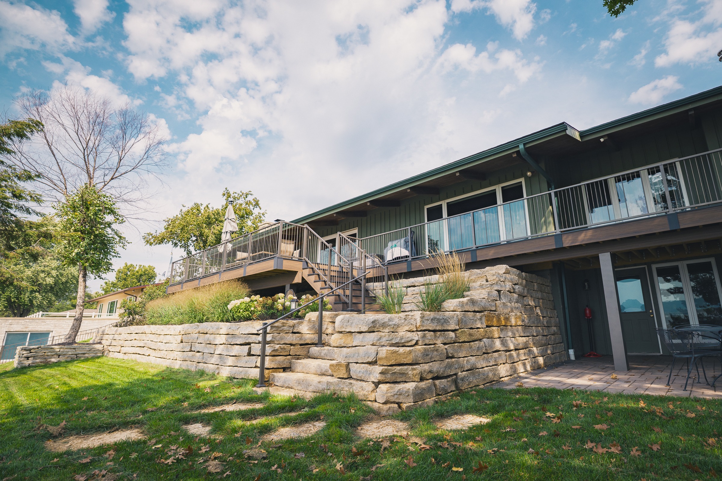 Modern home with elevated deck and stone wall