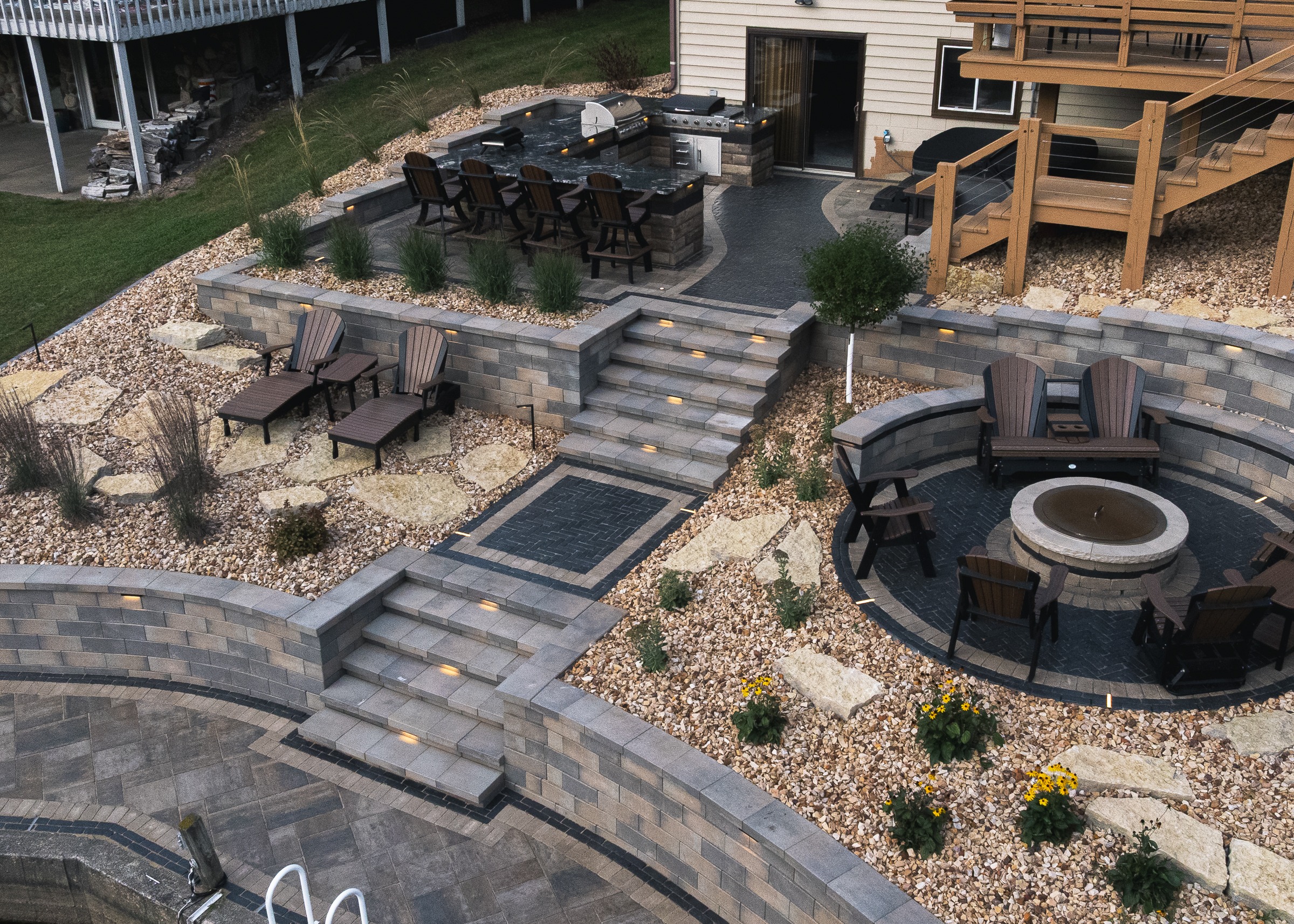 Multi-level backyard patio with fire pit and kitchen