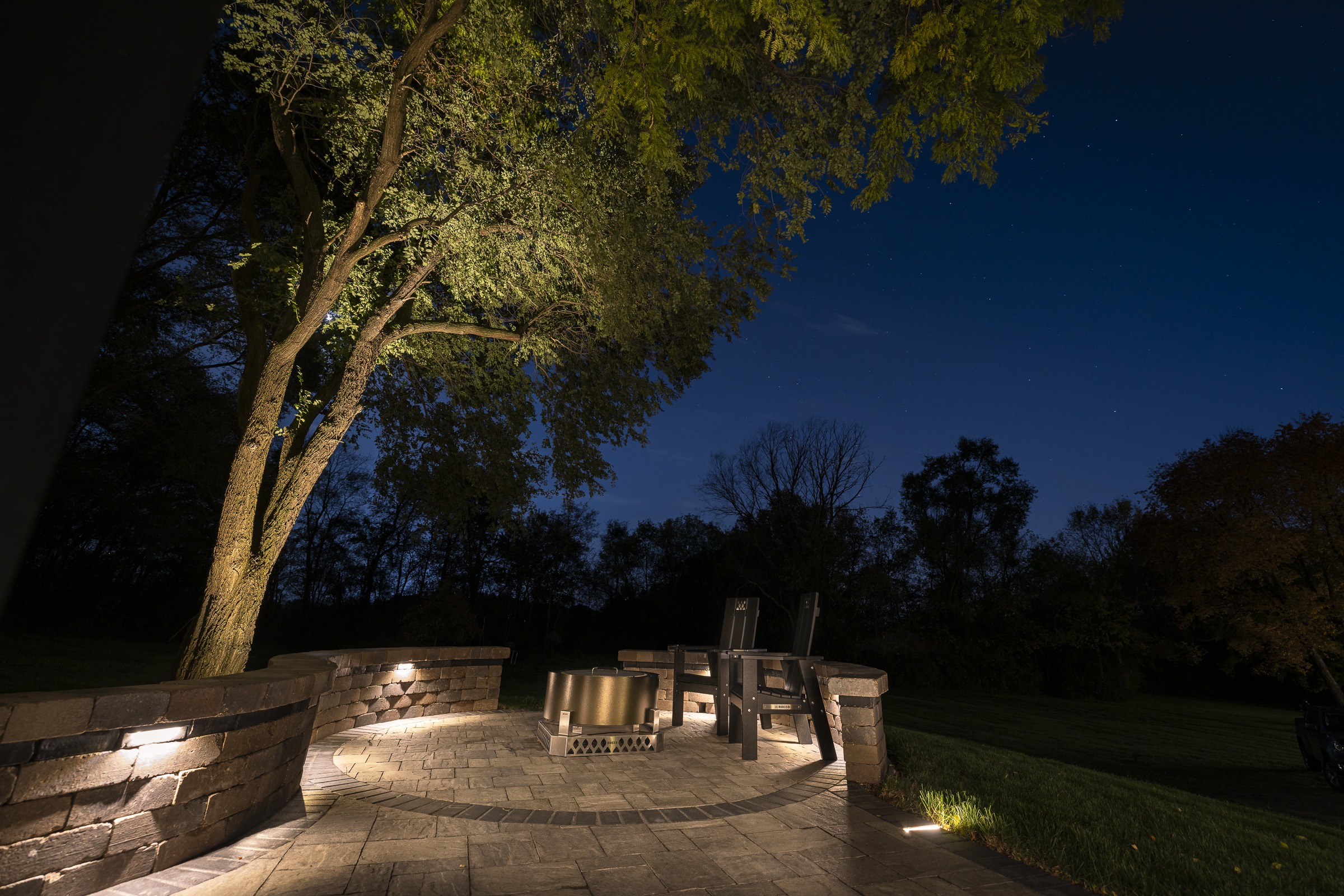 Illuminated backyard patio with fire pit at night