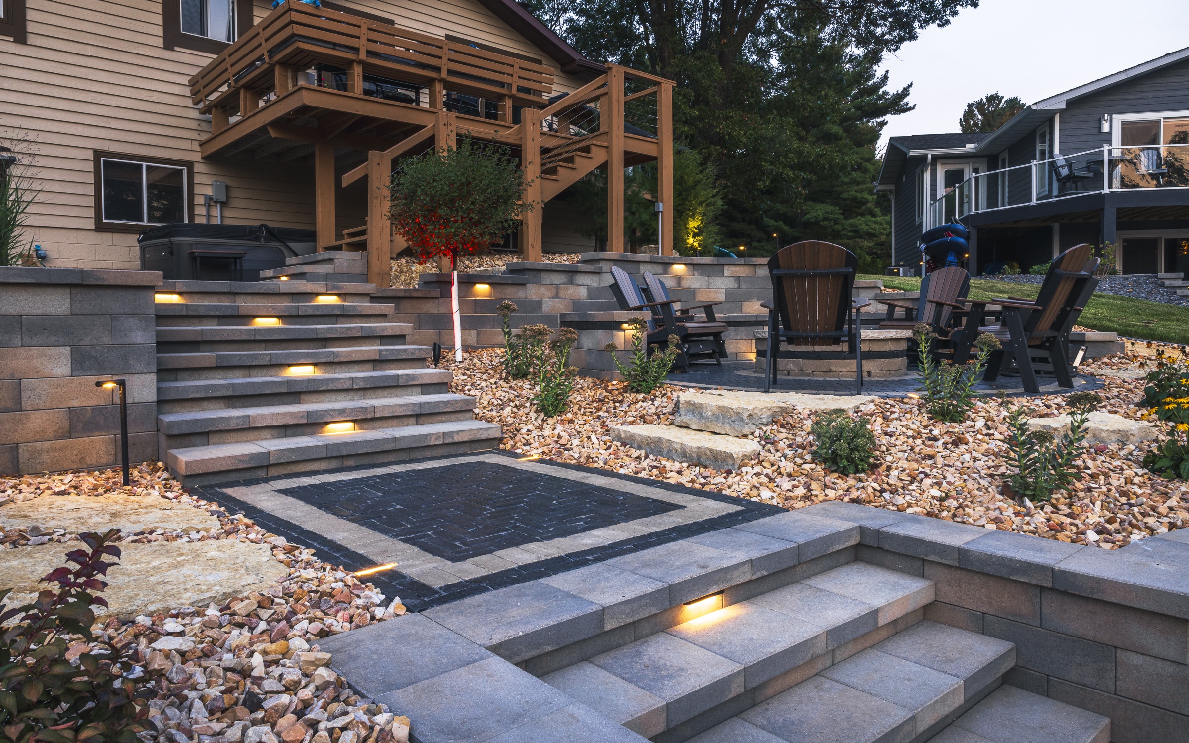 Tiered stone patio with lit steps and fire pit