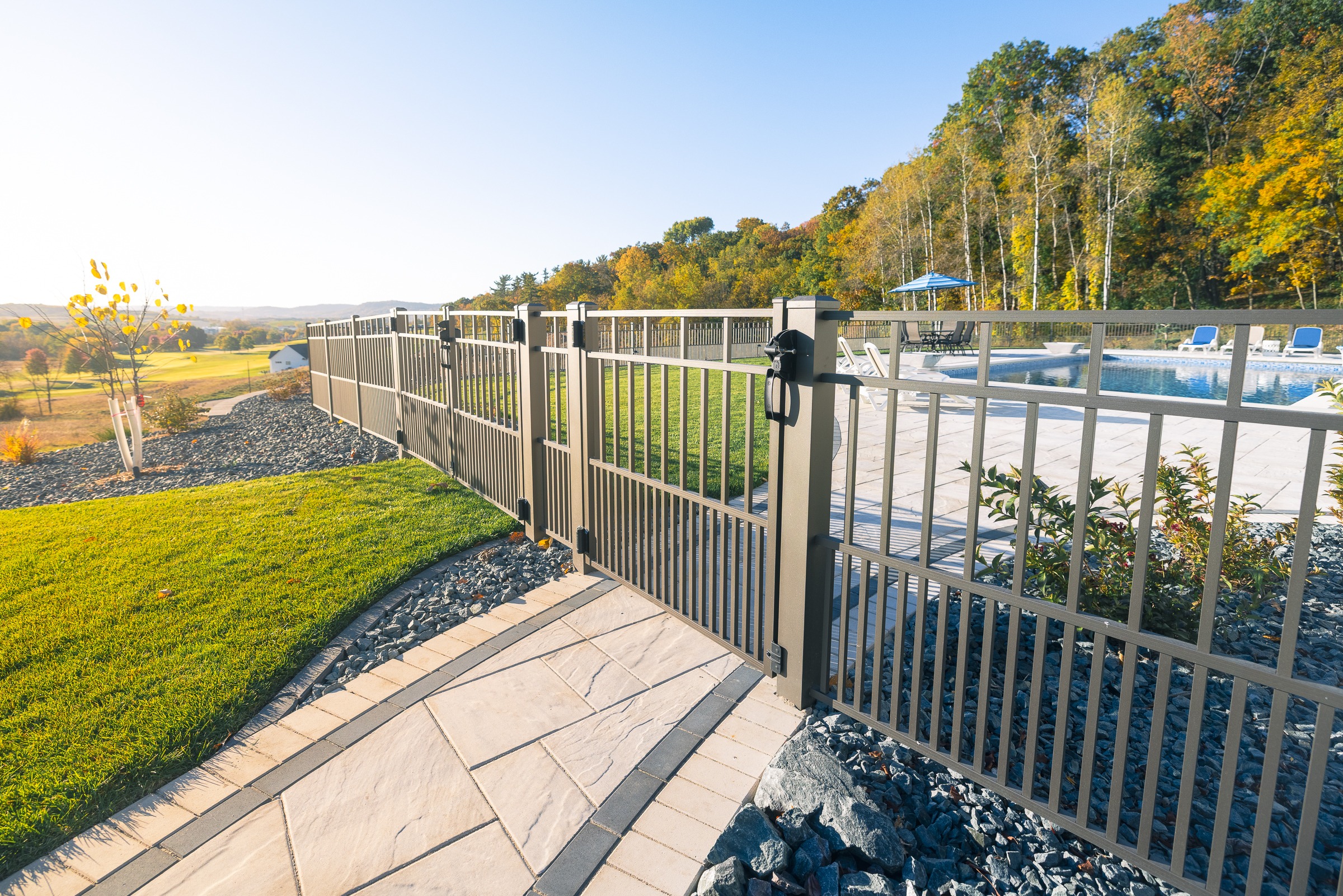 Metal fence surrounding backyard swimming pool in autumn