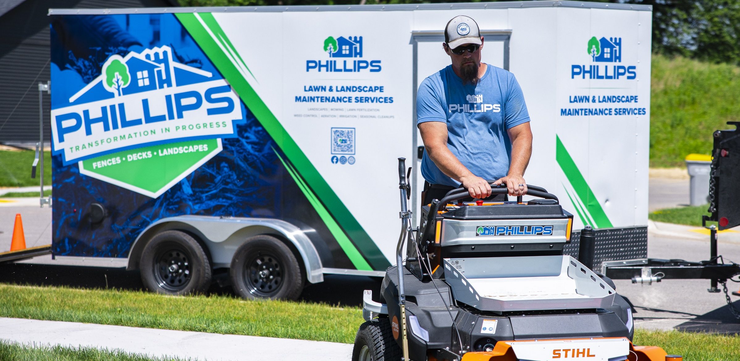 Landscaper mowing lawn beside branded service trailer