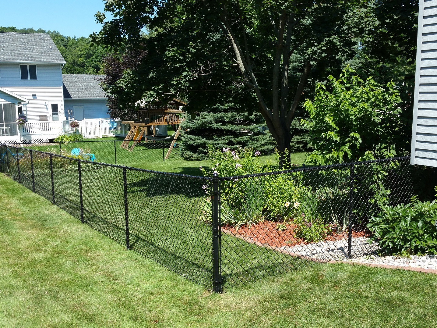 Black chain-link fence around suburban backyard