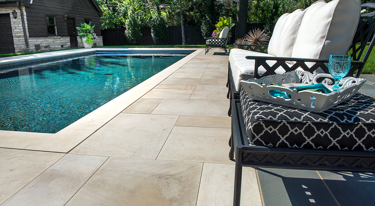 Backyard swimming pool with stone patio and lounge seating