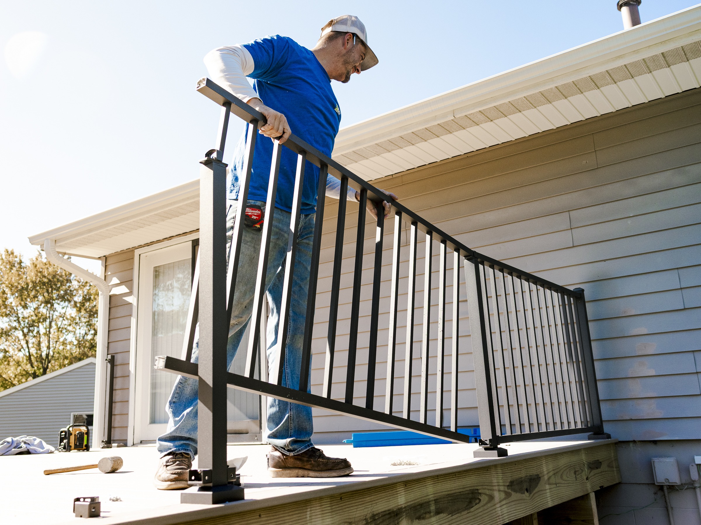 Man installing Westbury aluminum deck railing outdoors on a new composite deck.