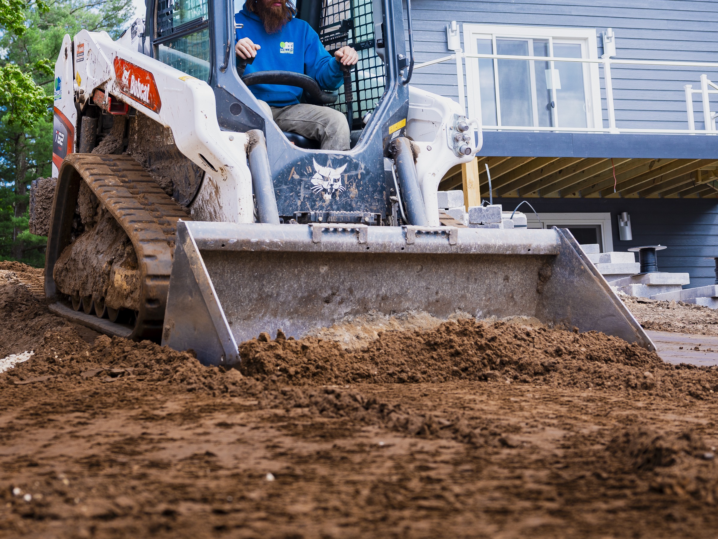 Skid-steer loader grading soil to improve drainage.