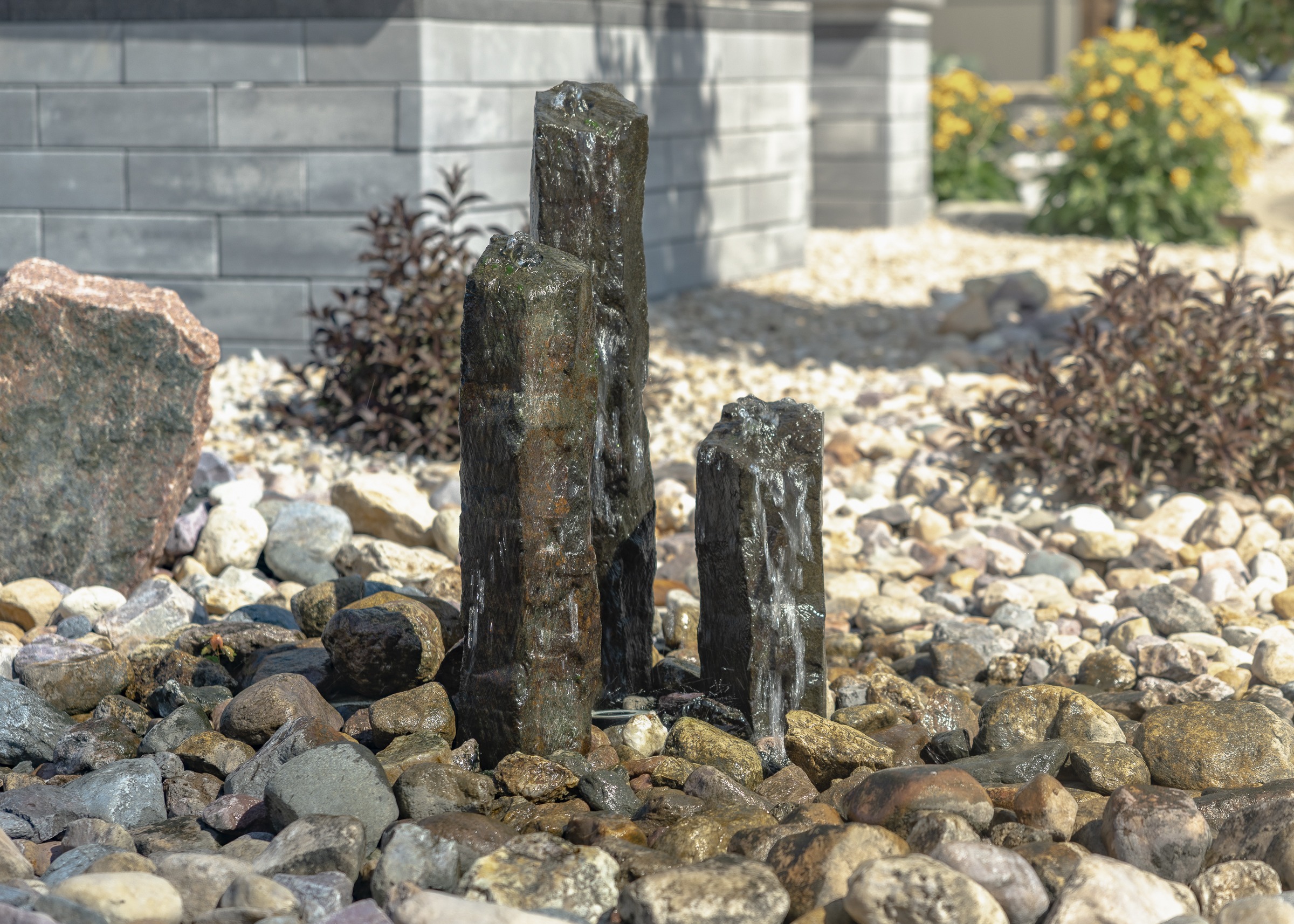 Three stone pillars fountain in pebble garden