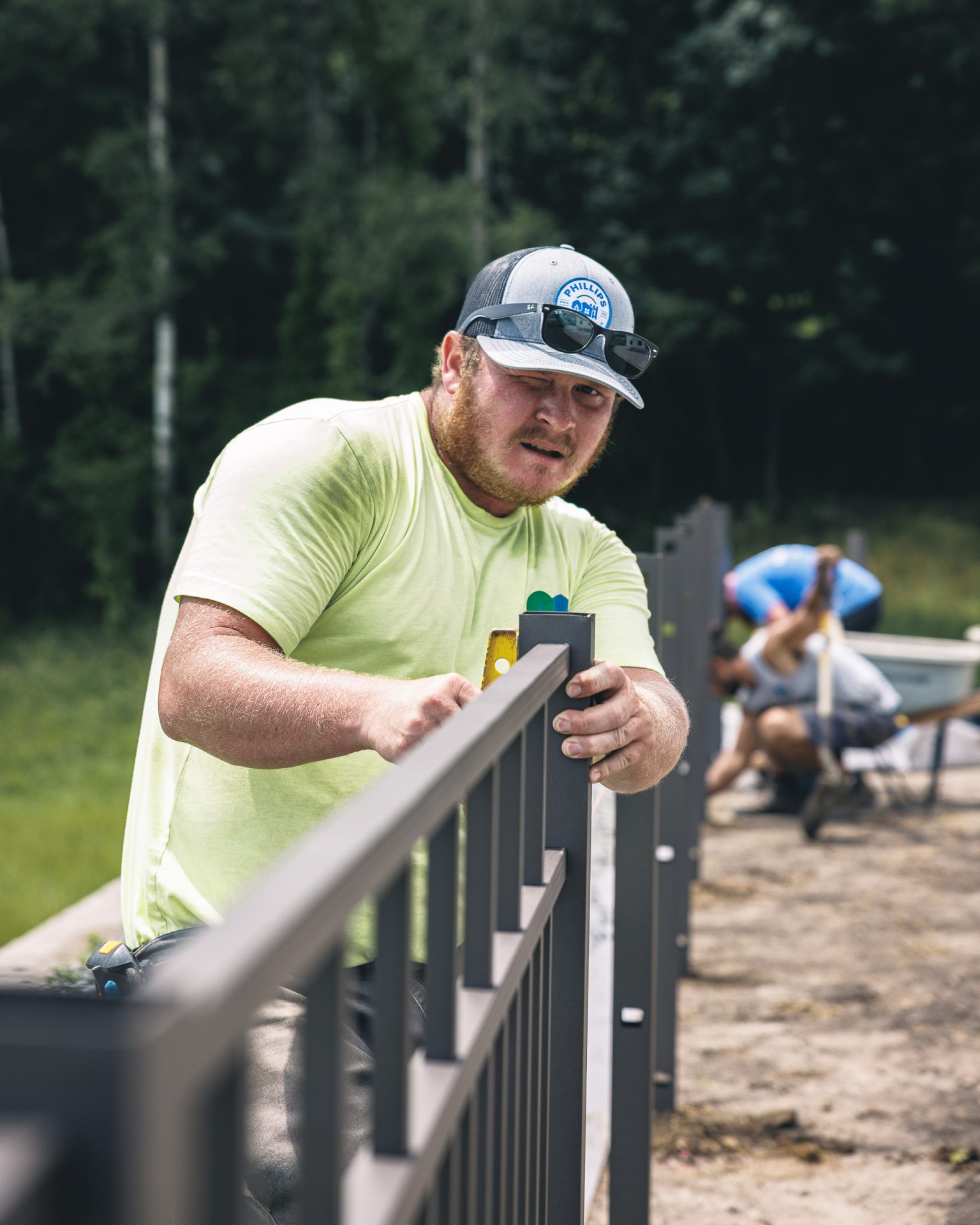 Man installing aluminum fence with level tool