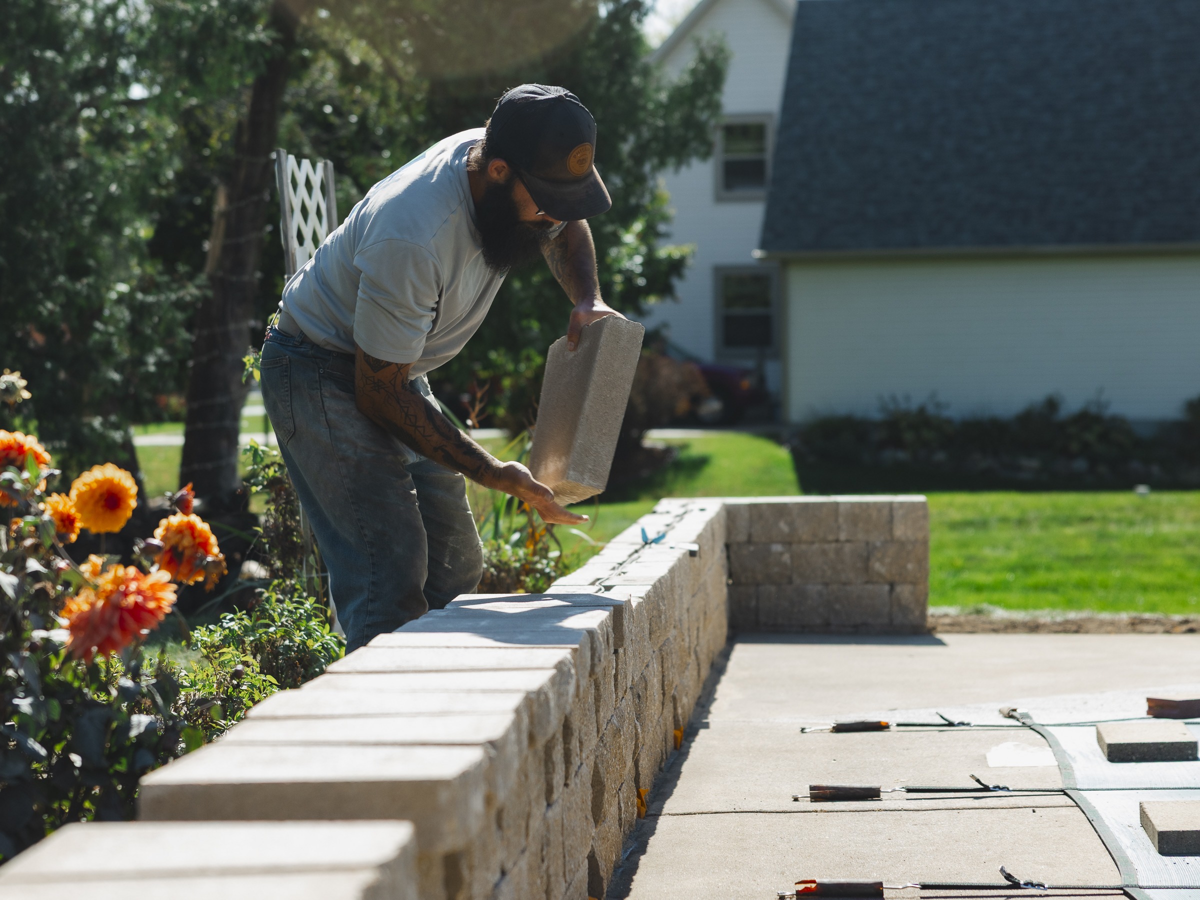 Man placing stone block on seat wall