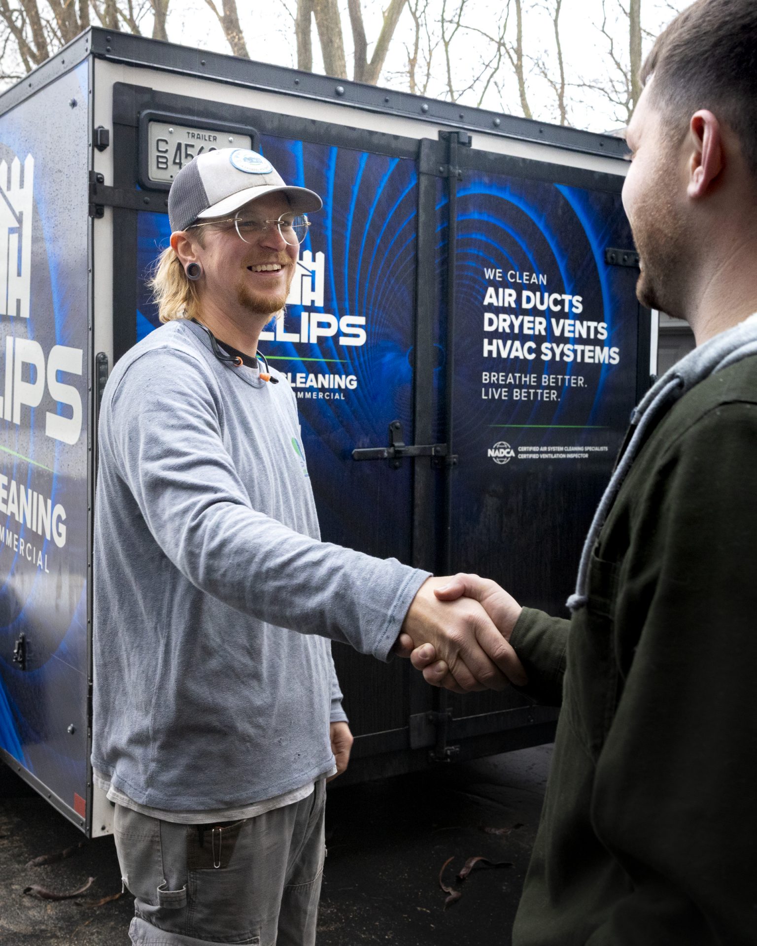 HVAC technician shaking hands with customer by trailer