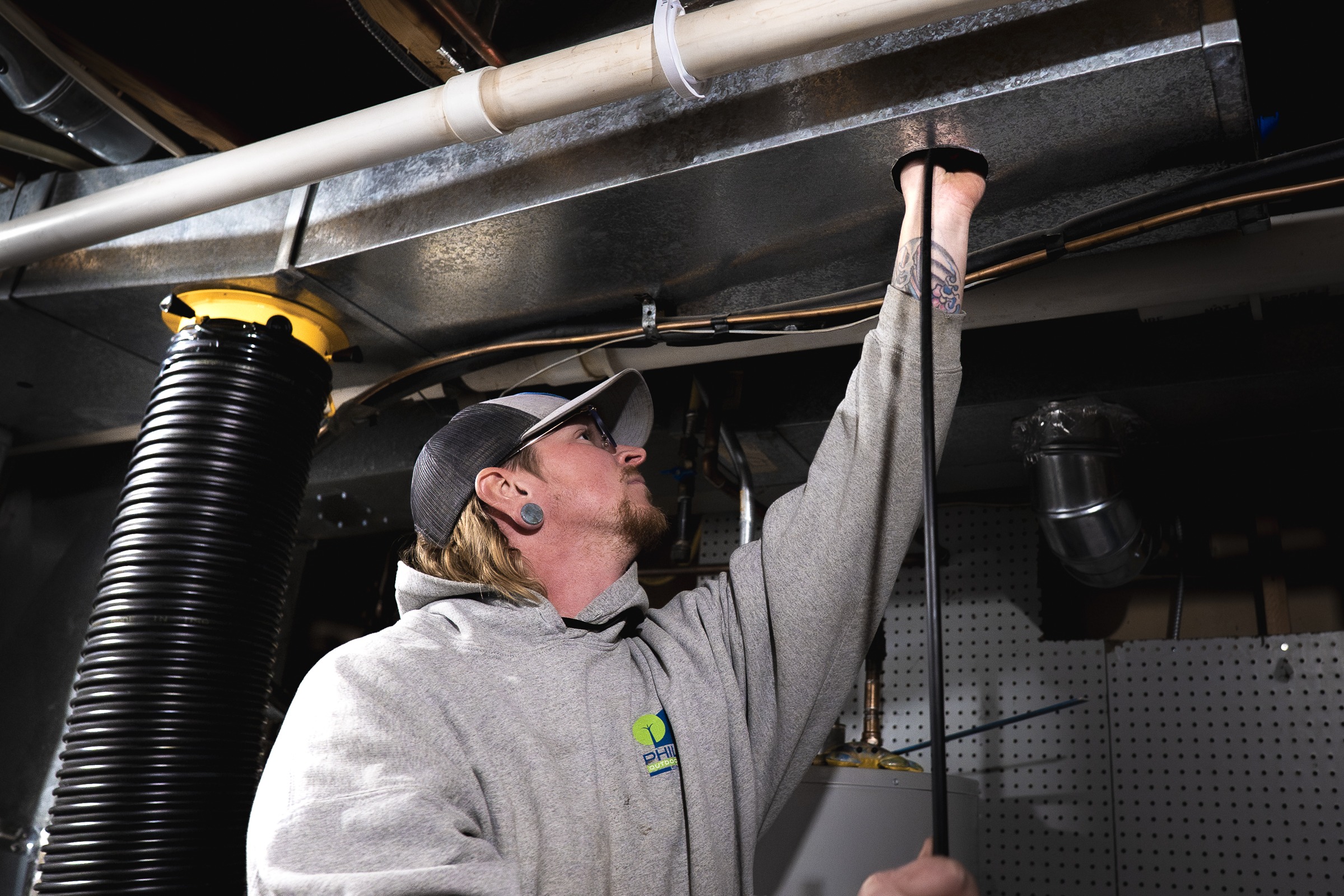Technician inspecting basement ductwork with tool