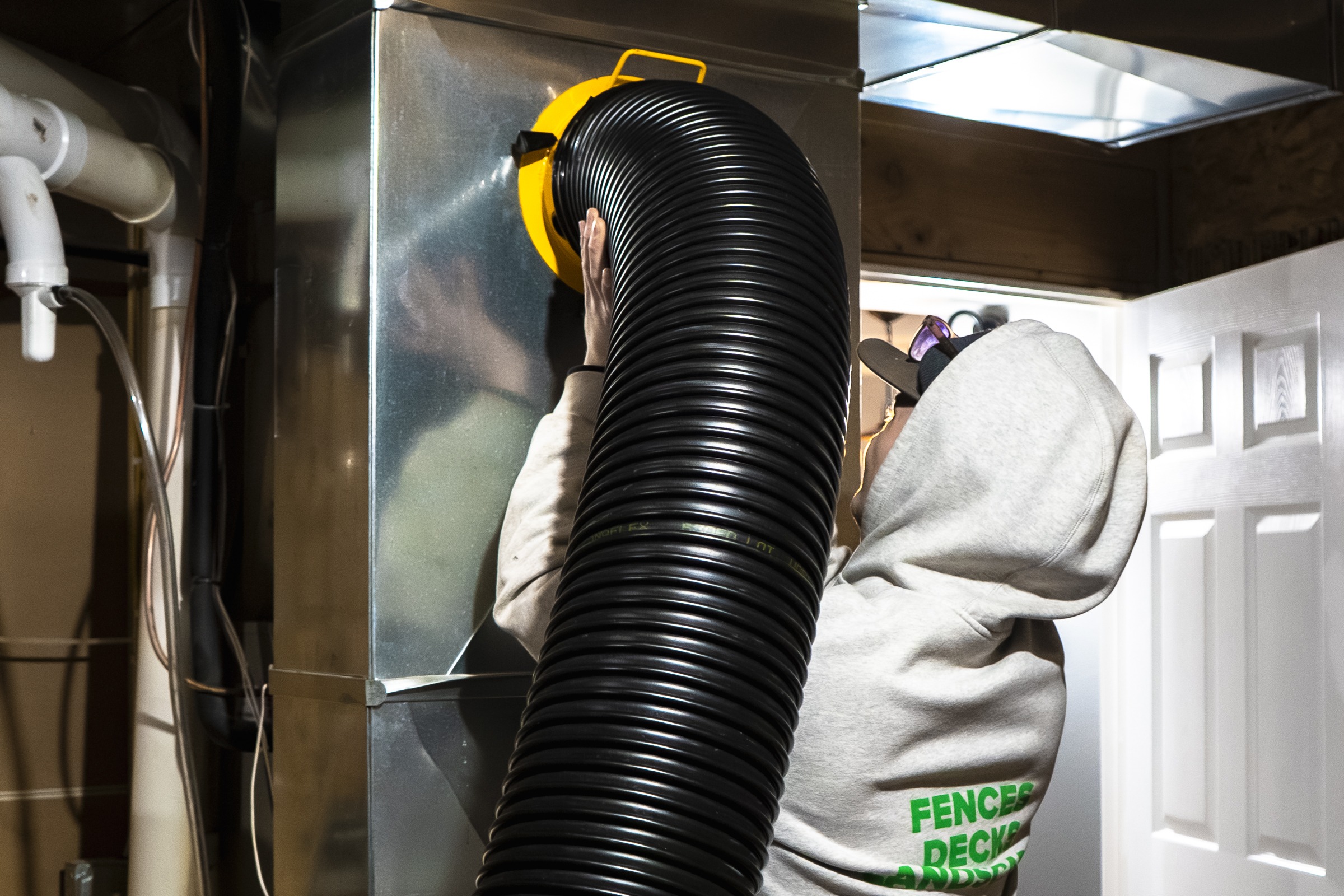 Technician attaching large hose to HVAC unit