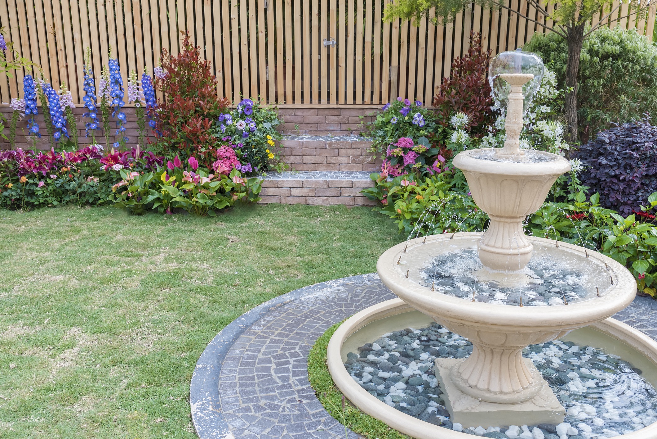 Tiered stone fountain in colorful landscaped garden