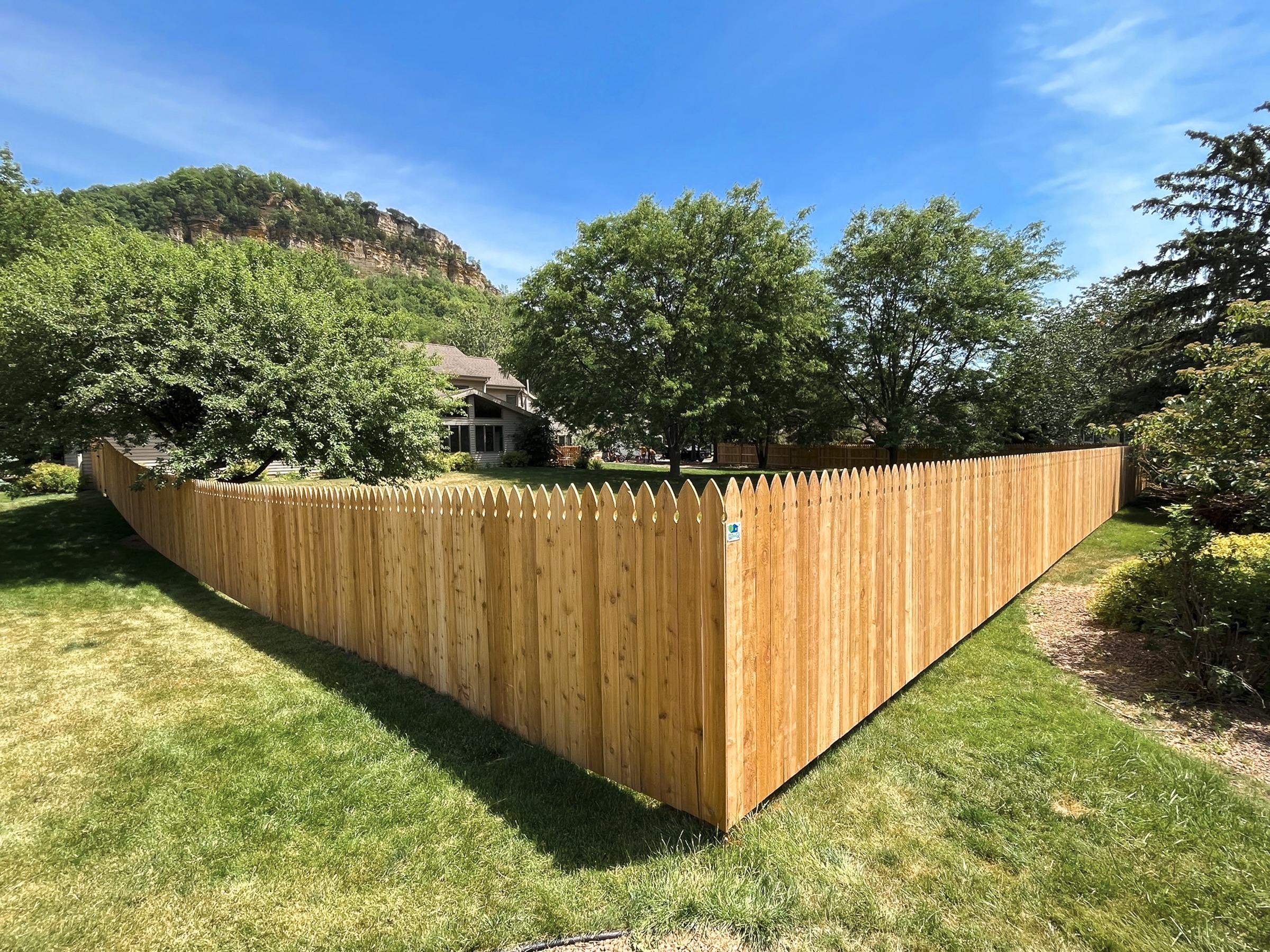 Wooden Cedar fence enclosing lush backyard lawn