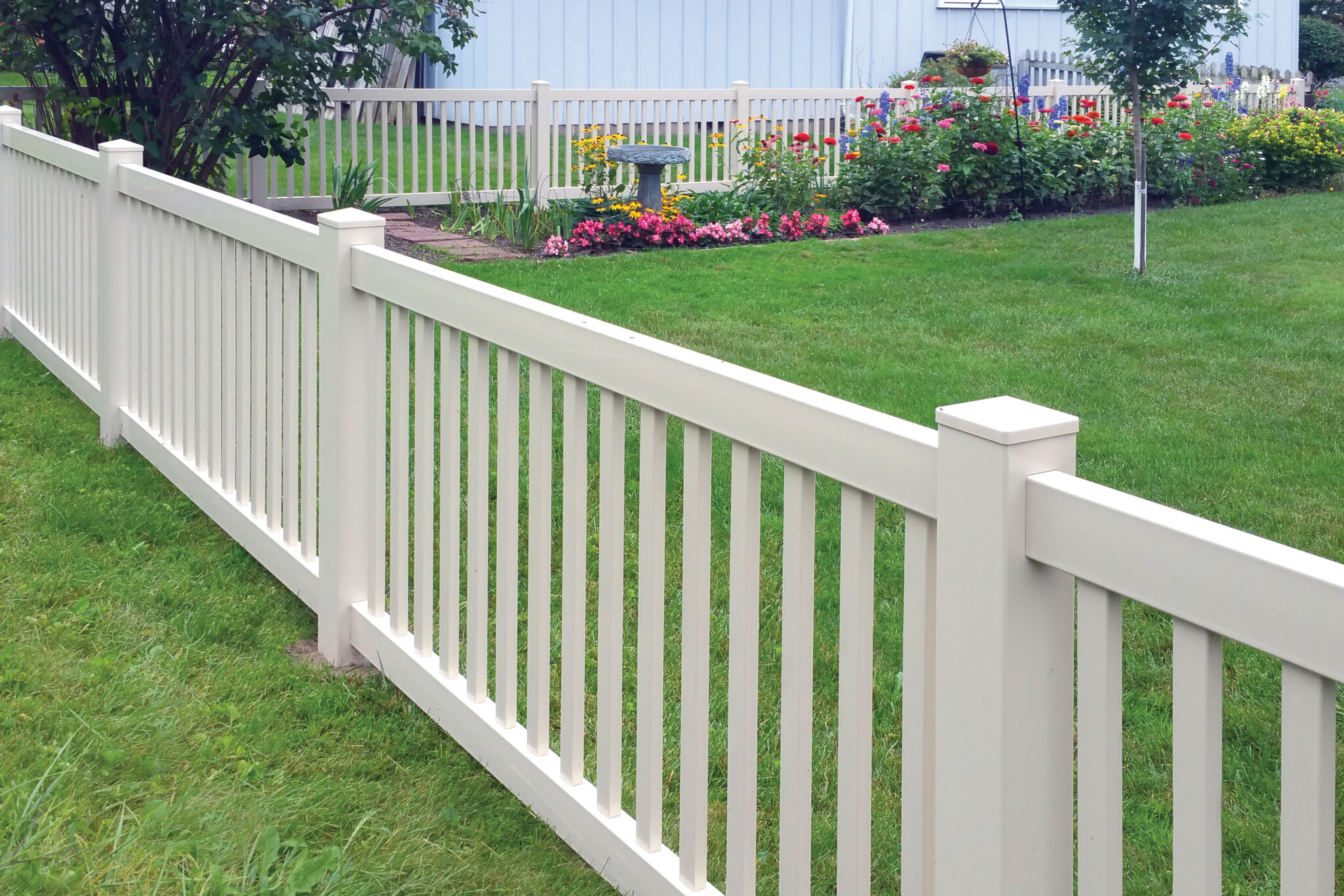 White vinyl fence surrounding landscaped backyard garden