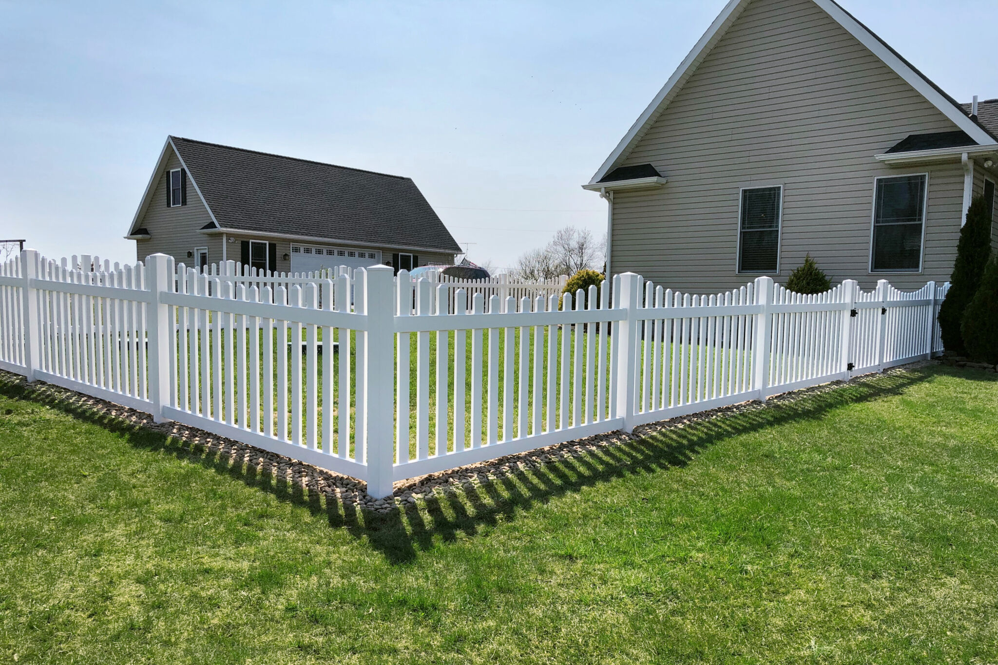 White vinyl picket fence around suburban backyard