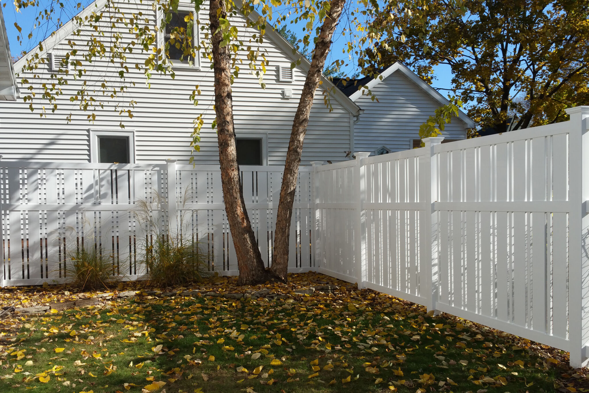 White vinyl fence surrounding backyard in autumn