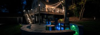Outdoor lighting with deck, patio, and uplighting on trees.